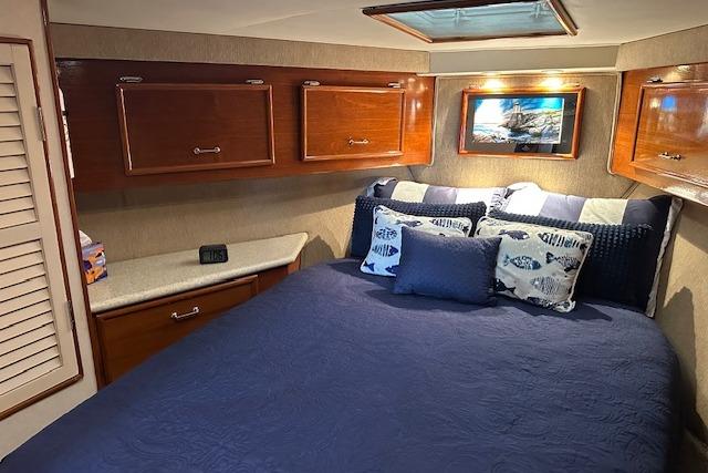 Cozy bedroom in 1988 Ocean 44' Super Sport yacht with blue bedding and wooden cabinets.