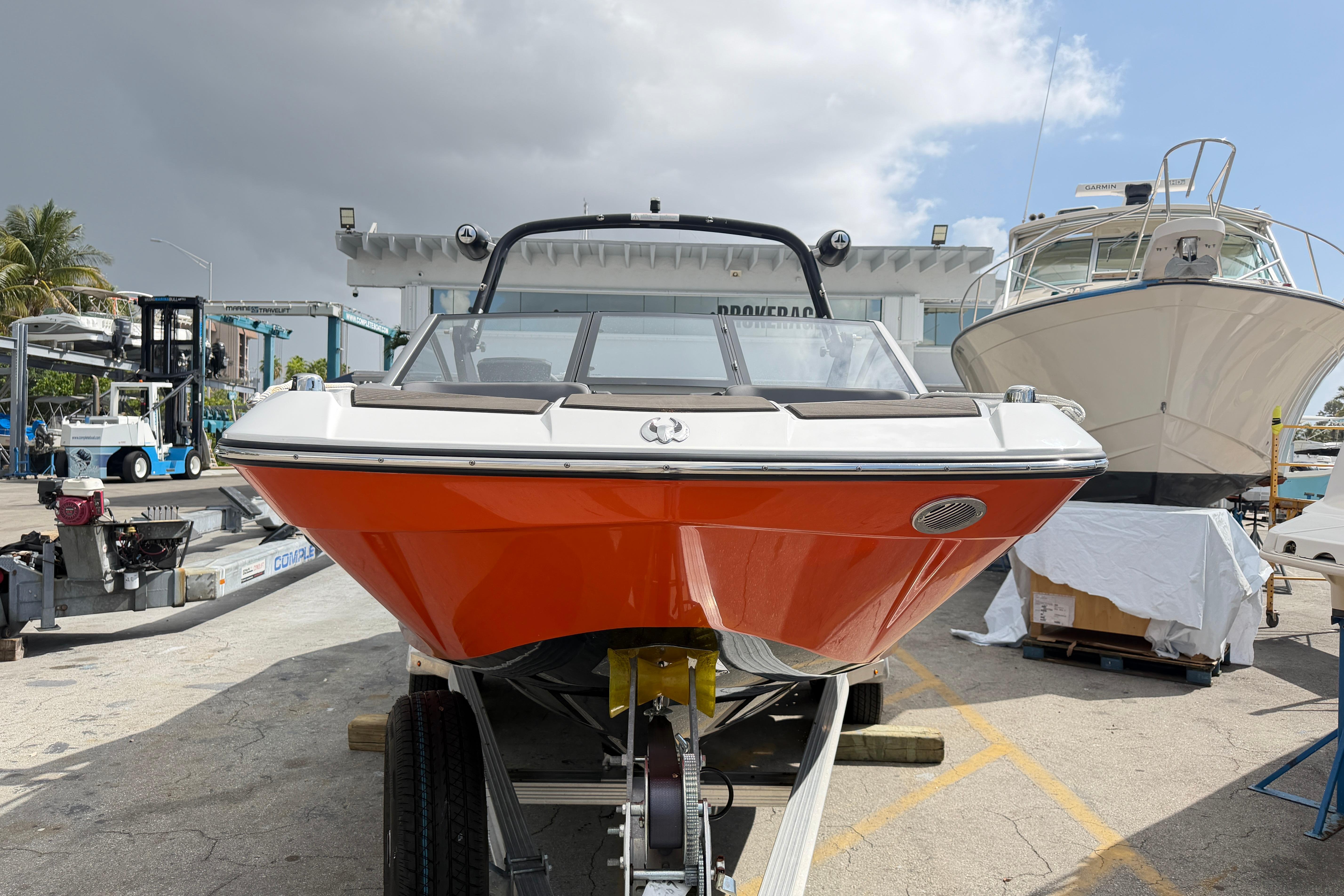 2026 Scarab 235 LX boat with orange hull on trailer, dockside view.