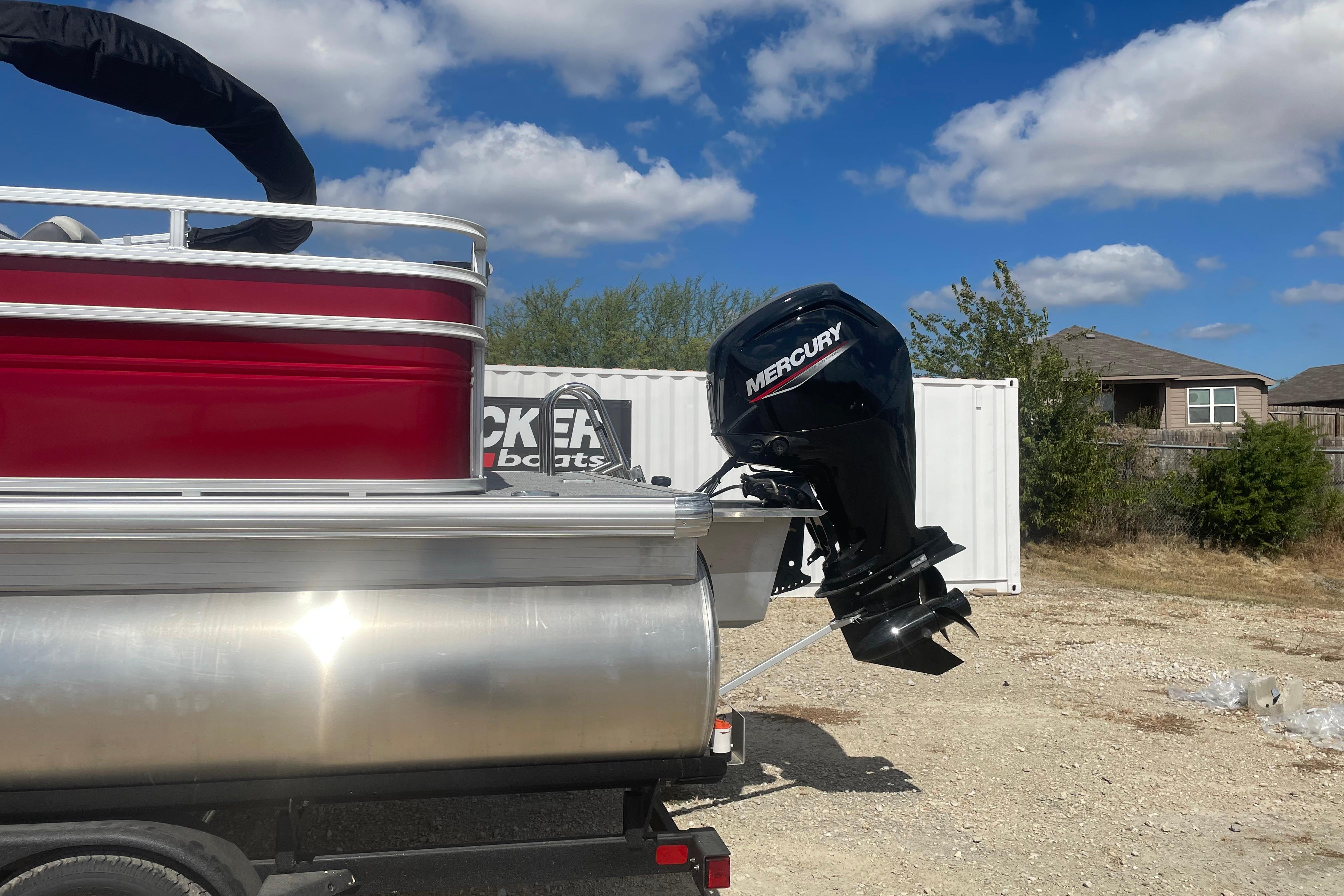 2026 Sun Tracker Fishin' Barge 22 DLX with Mercury outboard motor, parked outdoors.