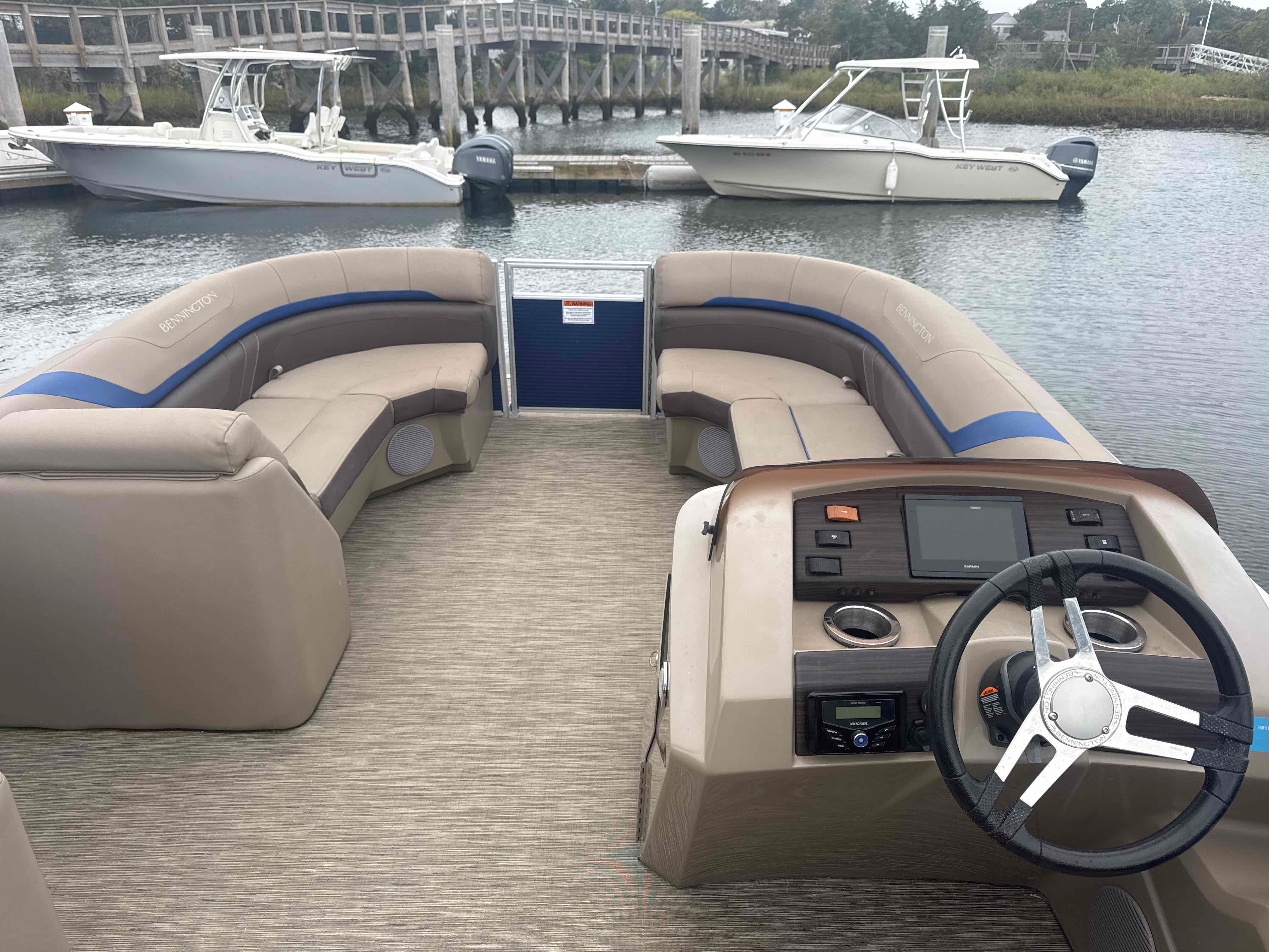 The image shows the cockpit of a 2023 Bennington 23SXSRC pontoon boat with beige seating.