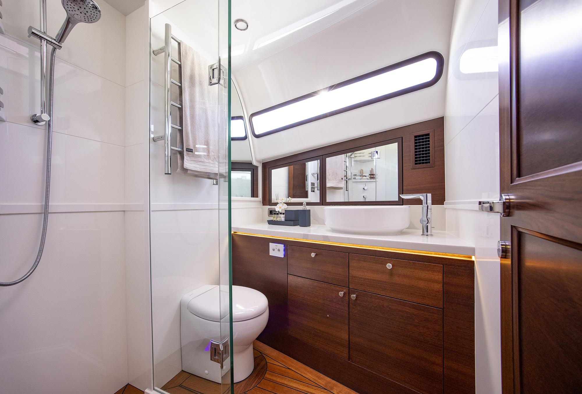 Luxurious bathroom in 2026 Grand Banks GB 85 yacht, featuring modern fixtures and elegant wood cabinetry.