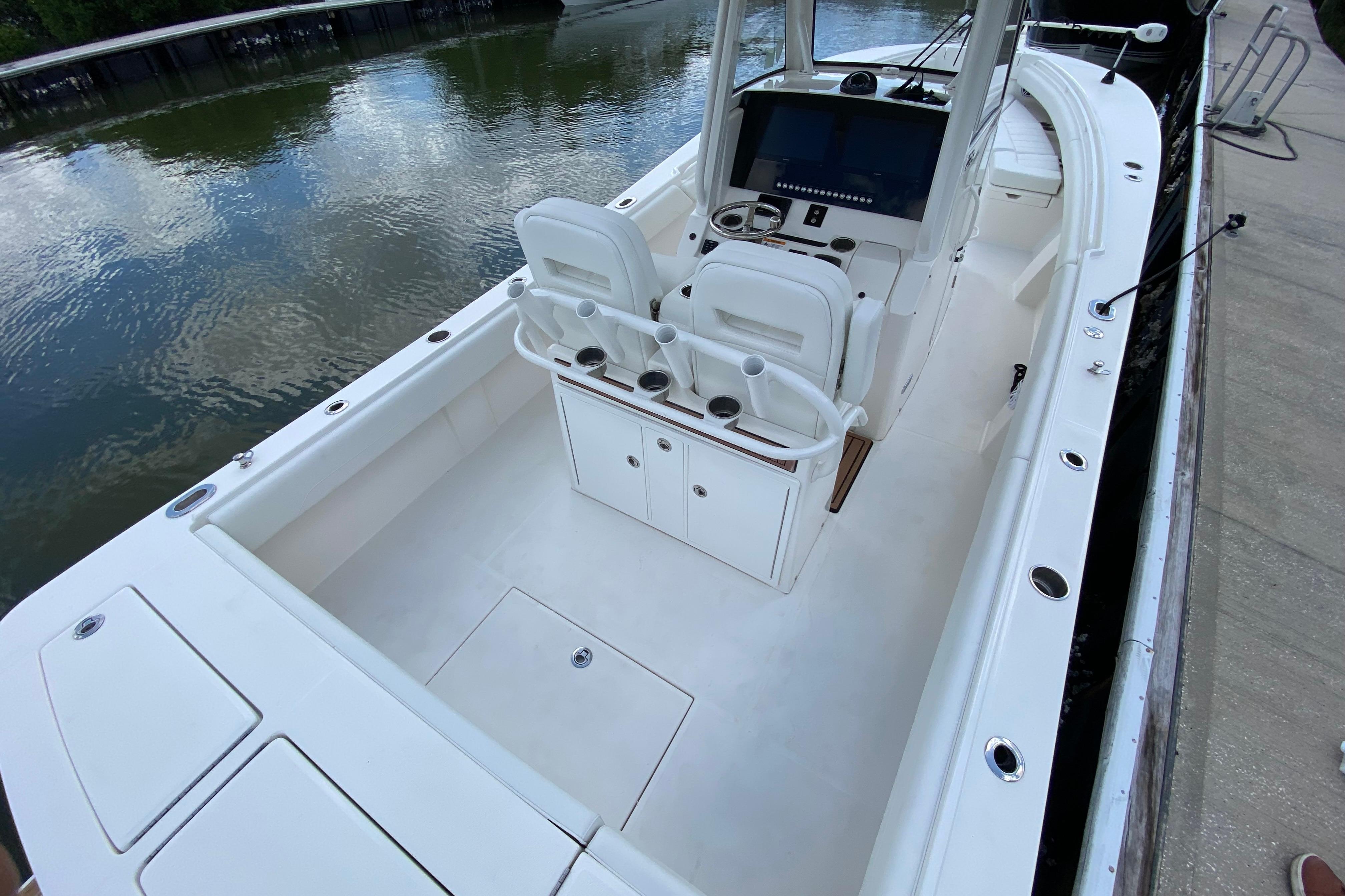 2021 Regulator 28 boat interior with helm, seating, and storage, docked by calm water.