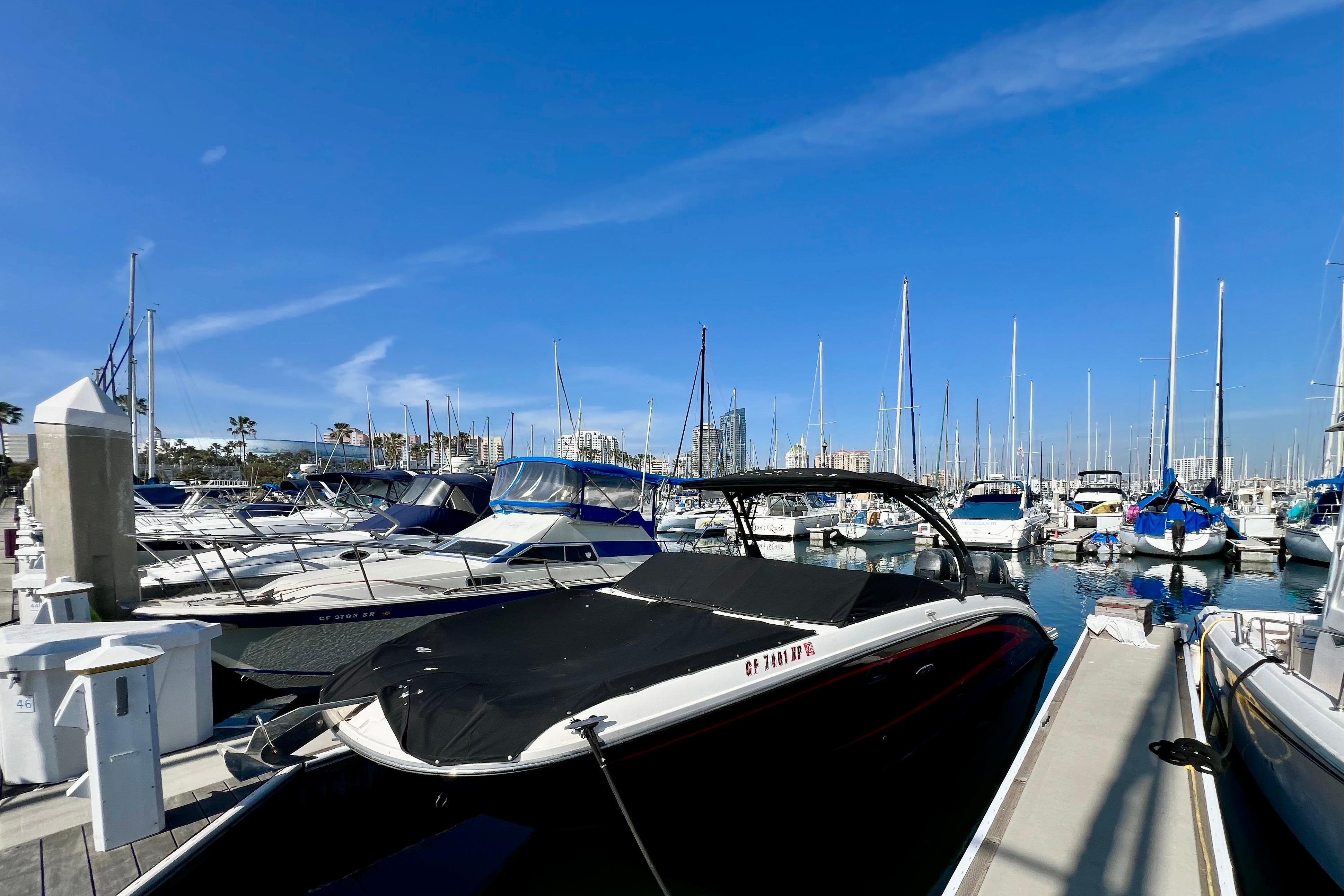 Marina with 2016 Sea Ray 290 Sundeck Outboard, surrounded by various boats under clear blue sky.