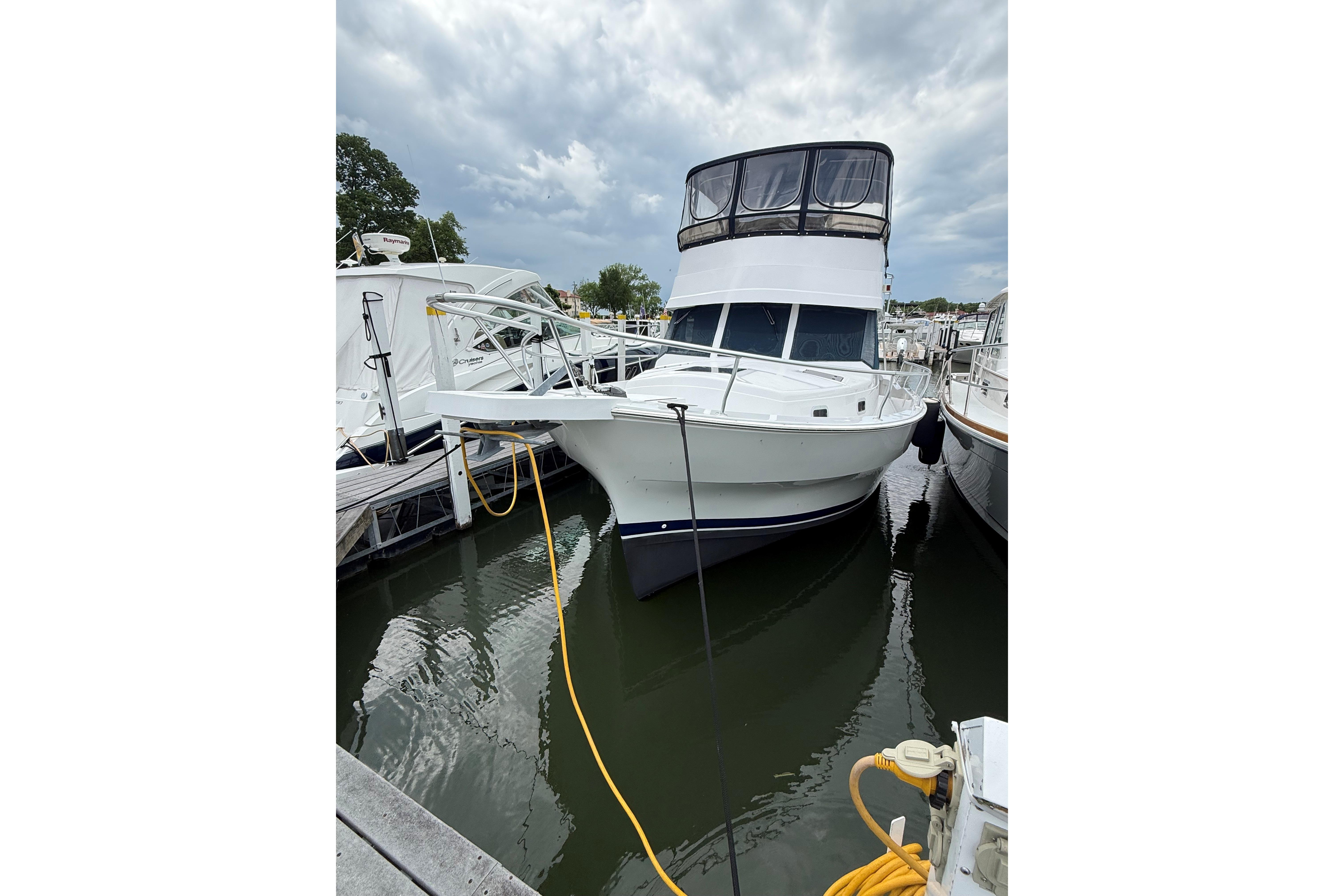 1999 Mainship 350 Trawler docked at marina under cloudy sky.