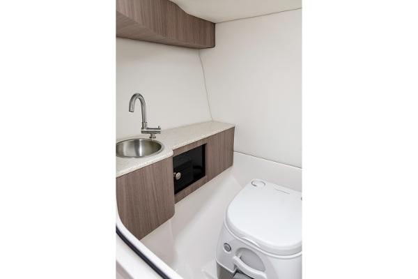 Manufacturer Provided Image: 2026 Regal LS6 boat interior with compact bathroom, featuring a sink and toilet.