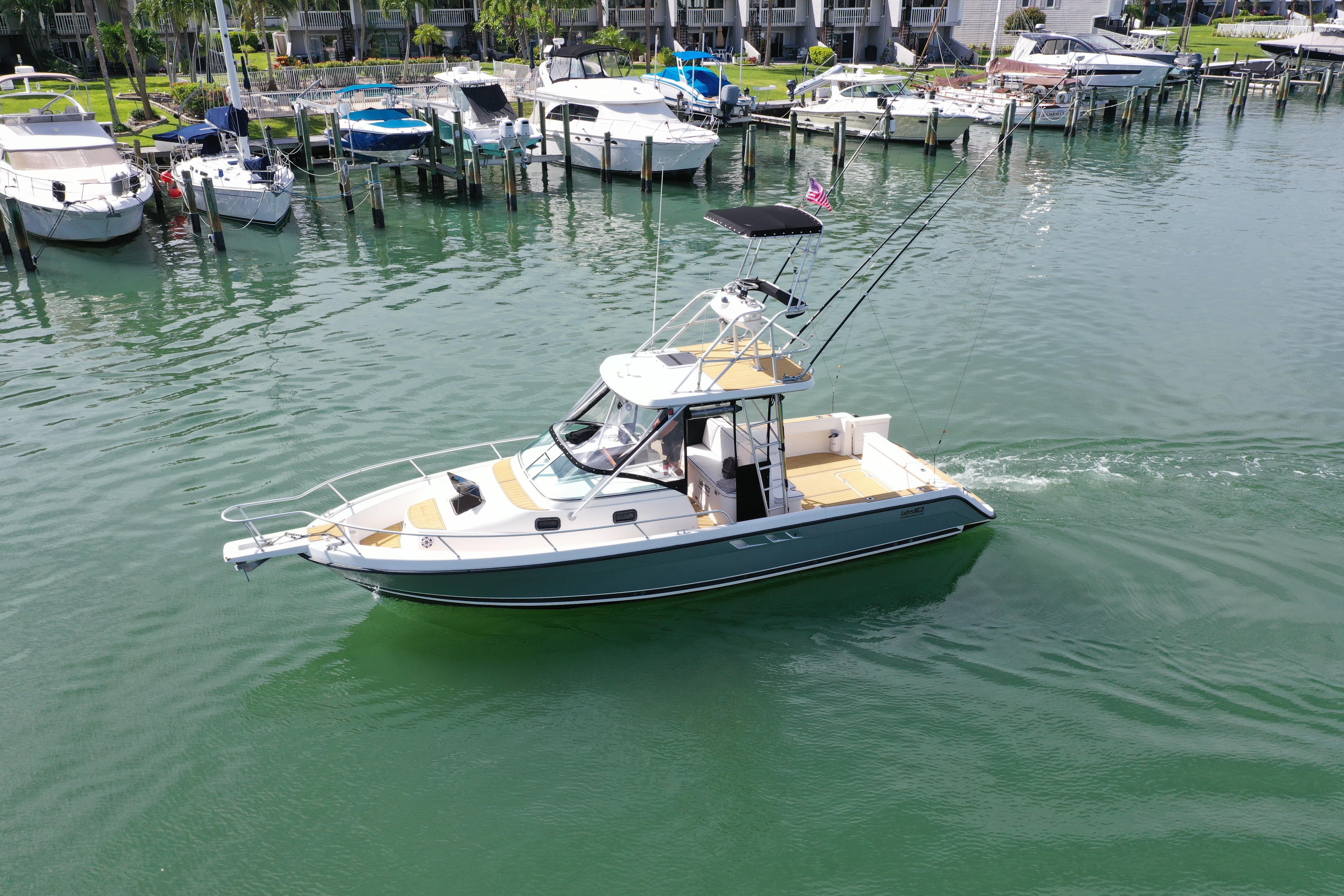 1992 Luhrs 300 Tournament boat cruising in a marina with docked vessels nearby.