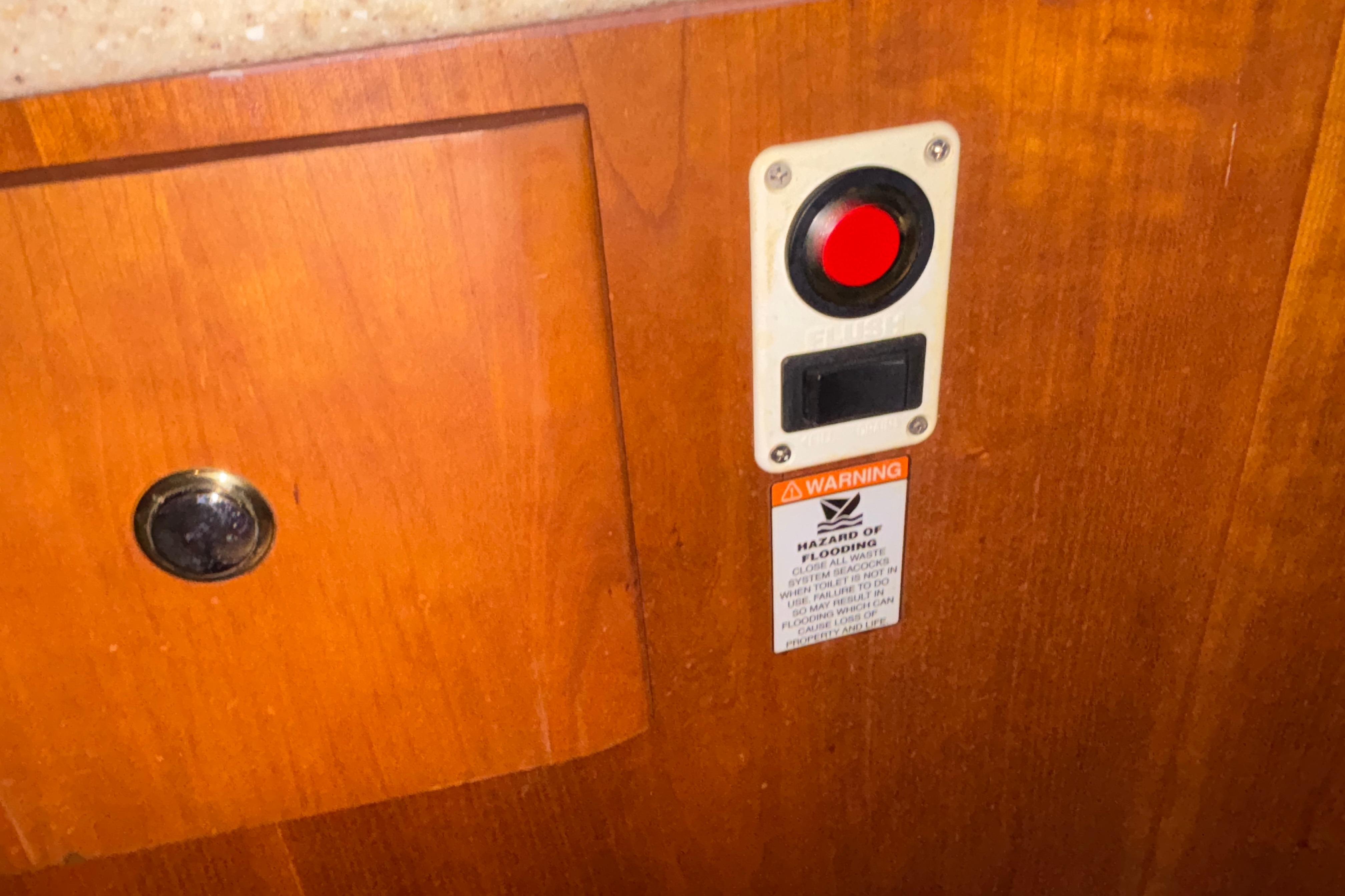 Red button and warning label on 2001 Silverton 410 Sport Bridge wooden panel.