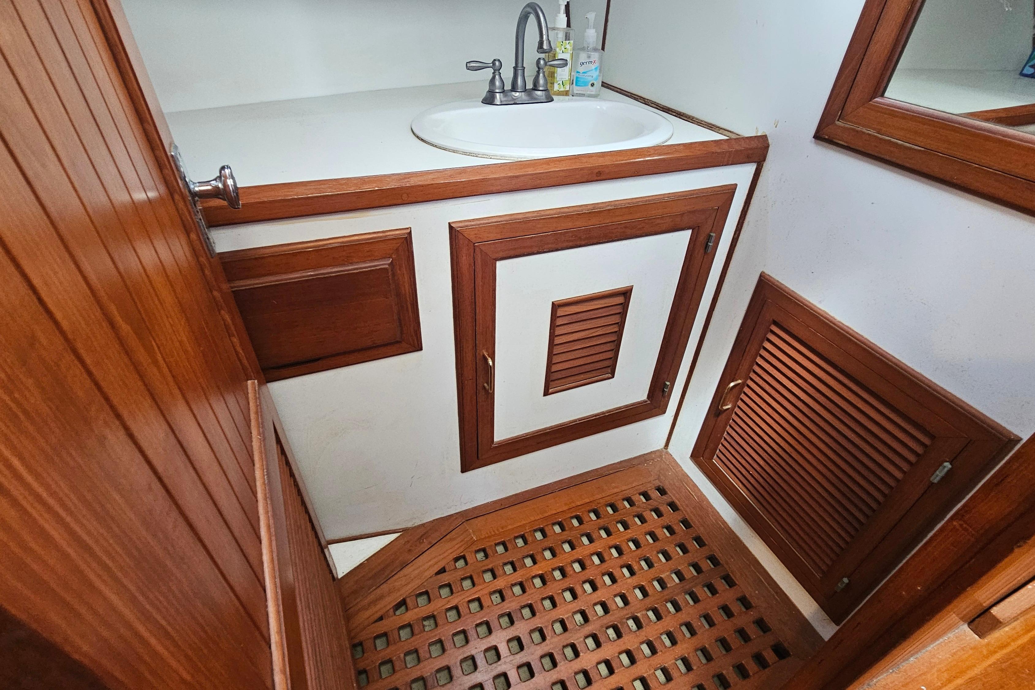 Wood-paneled bathroom interior of 1988 Overseas Monk 42 yacht with sink and storage cabinets.