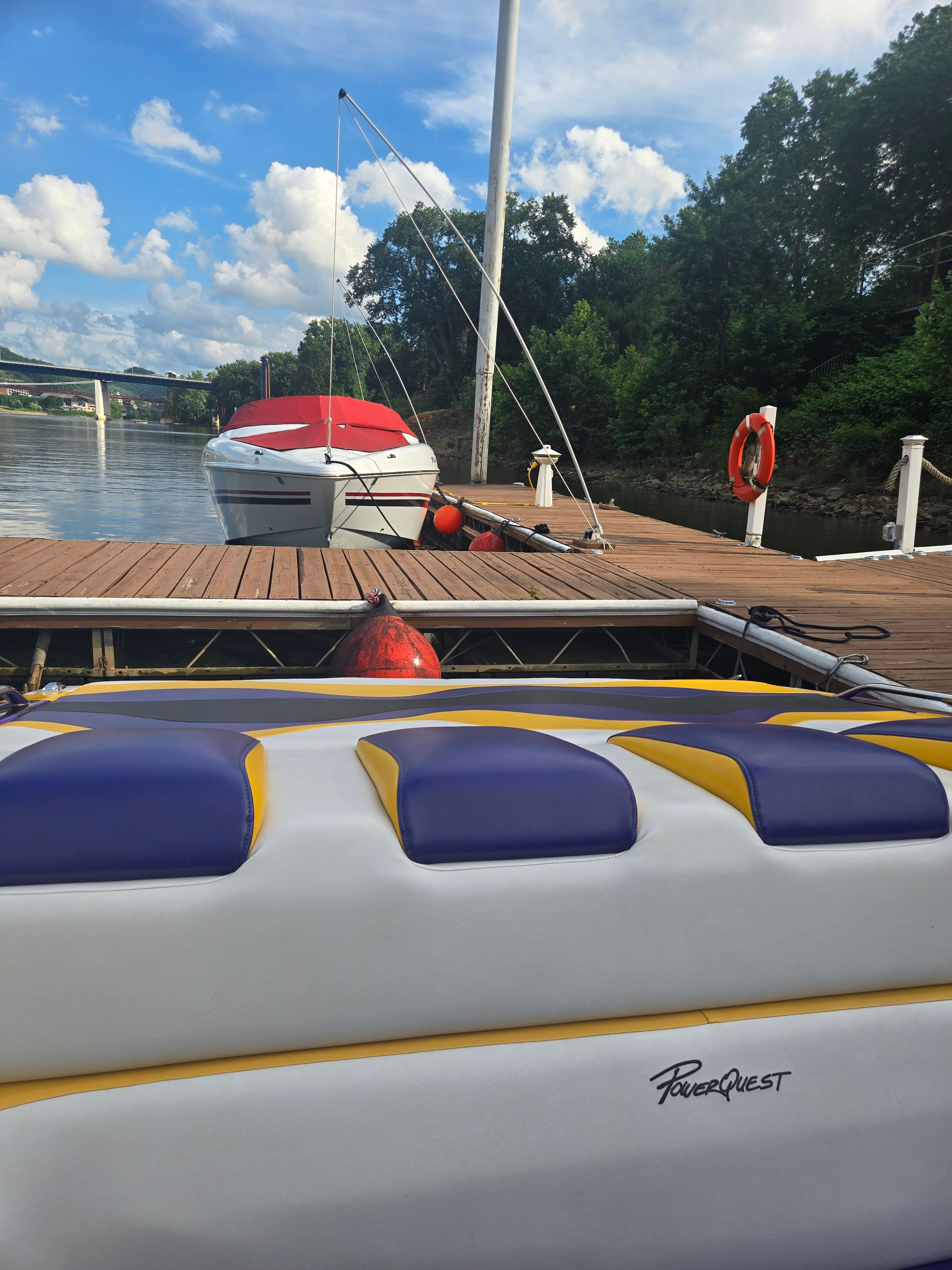 A Powerquest boat docked at a wooden pier, surrounded by trees and a lifebuoy.