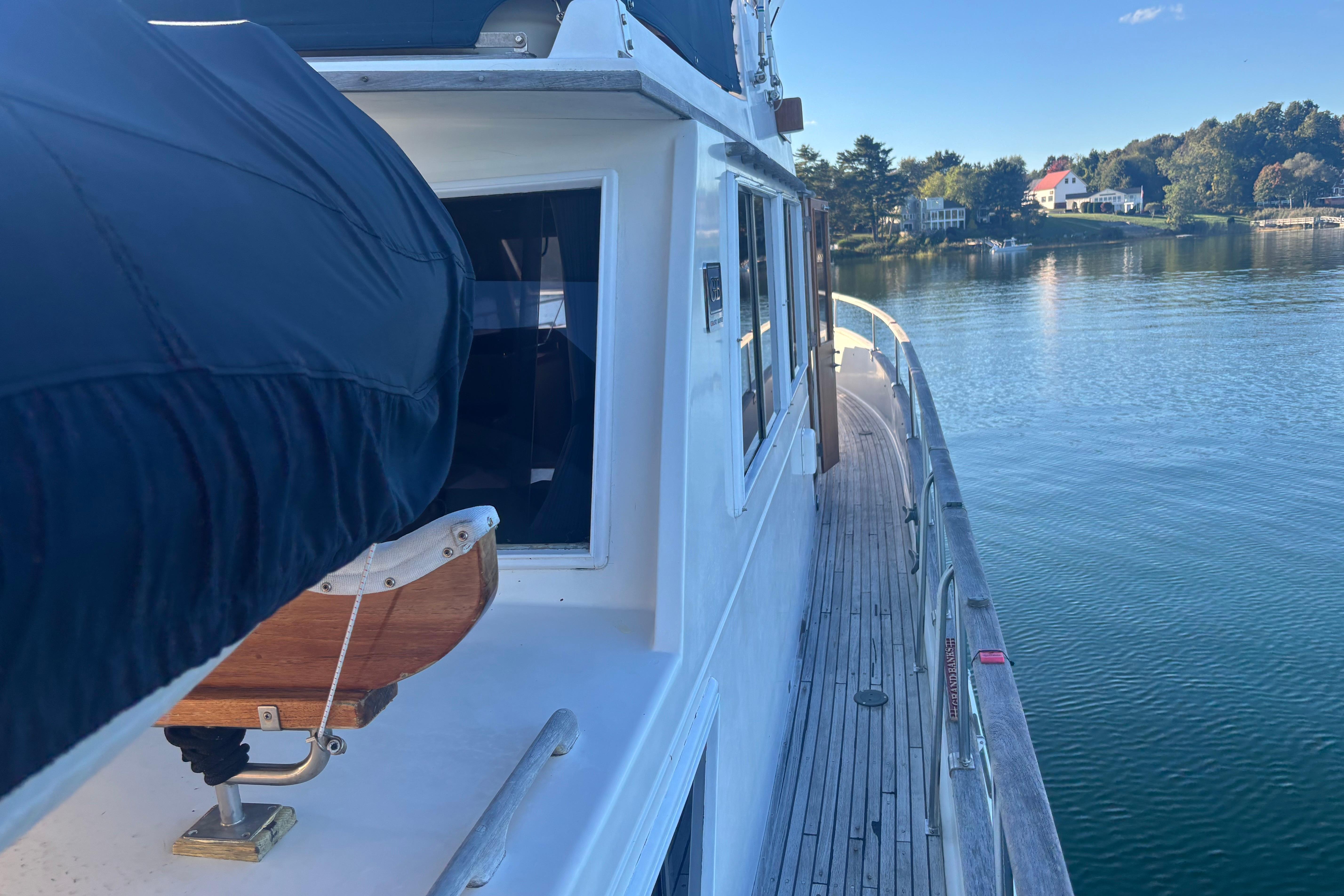 1989 Grand Banks 46 Classic yacht on serene water, showcasing deck and scenic shoreline.