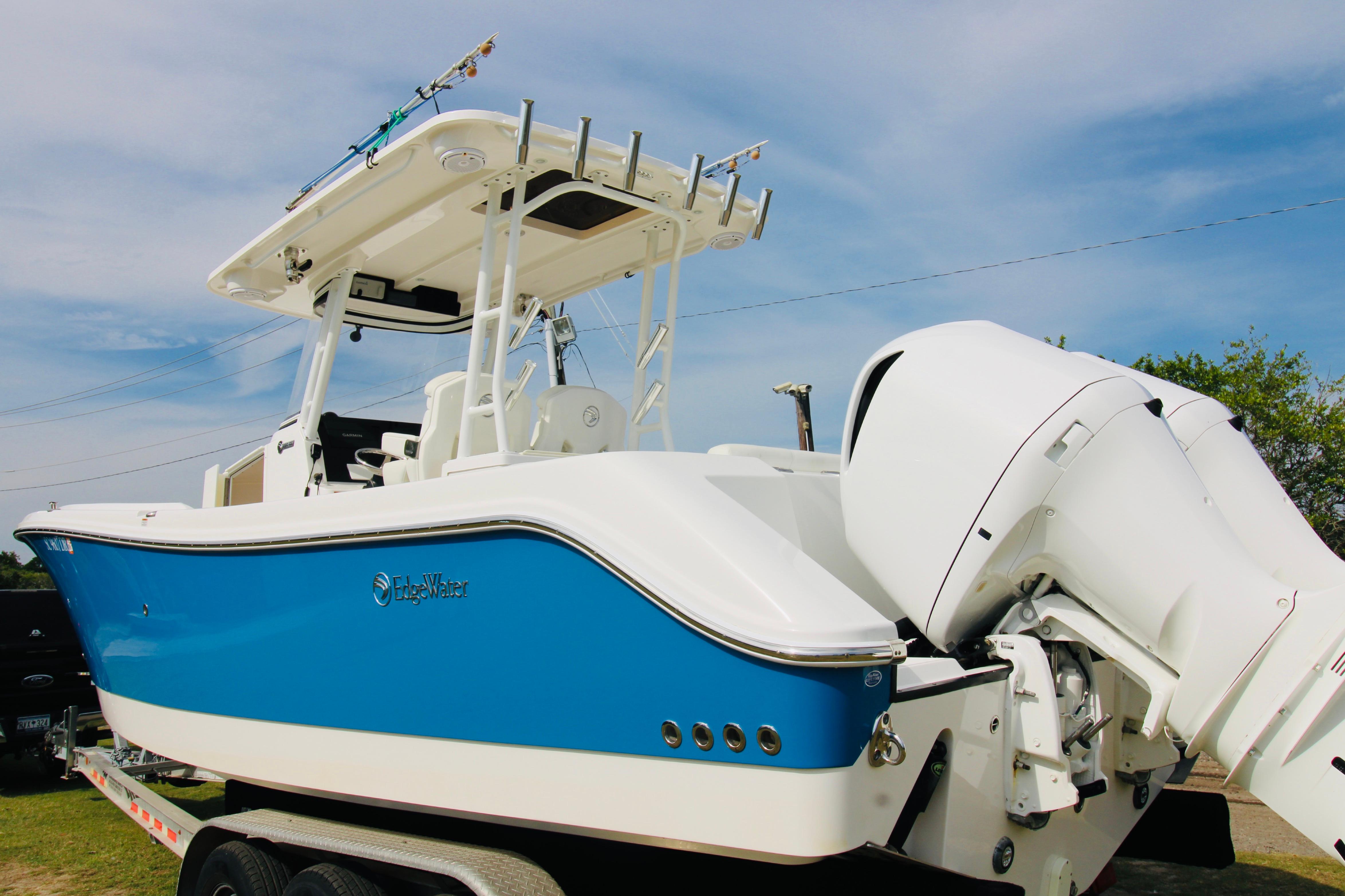 2022 Edgewater 280CC boat with blue hull and dual outboard engines on trailer.