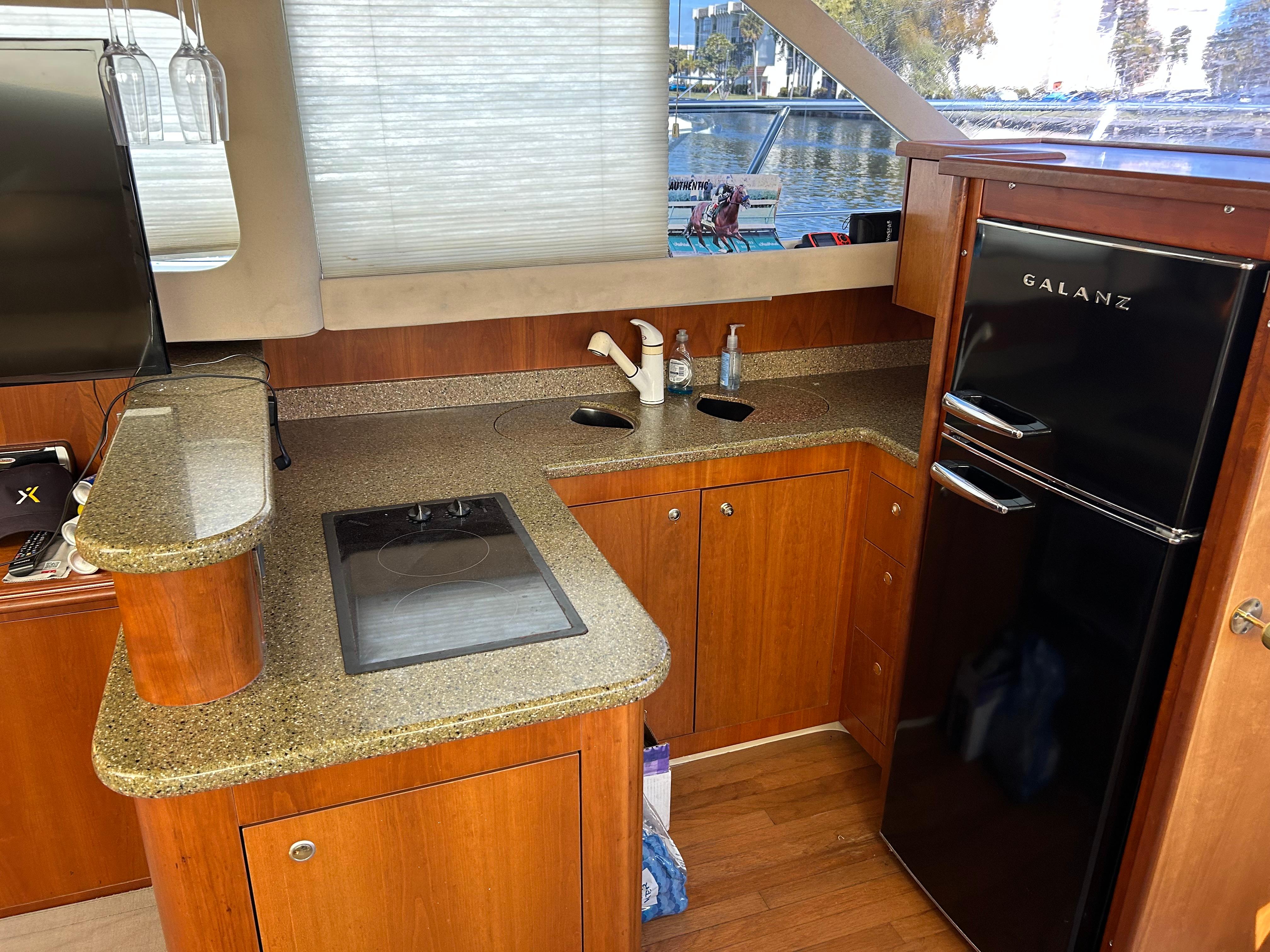 Interior of 2001 Cruisers Yachts 4450 Express Motoryacht kitchen with wood cabinetry and appliances.