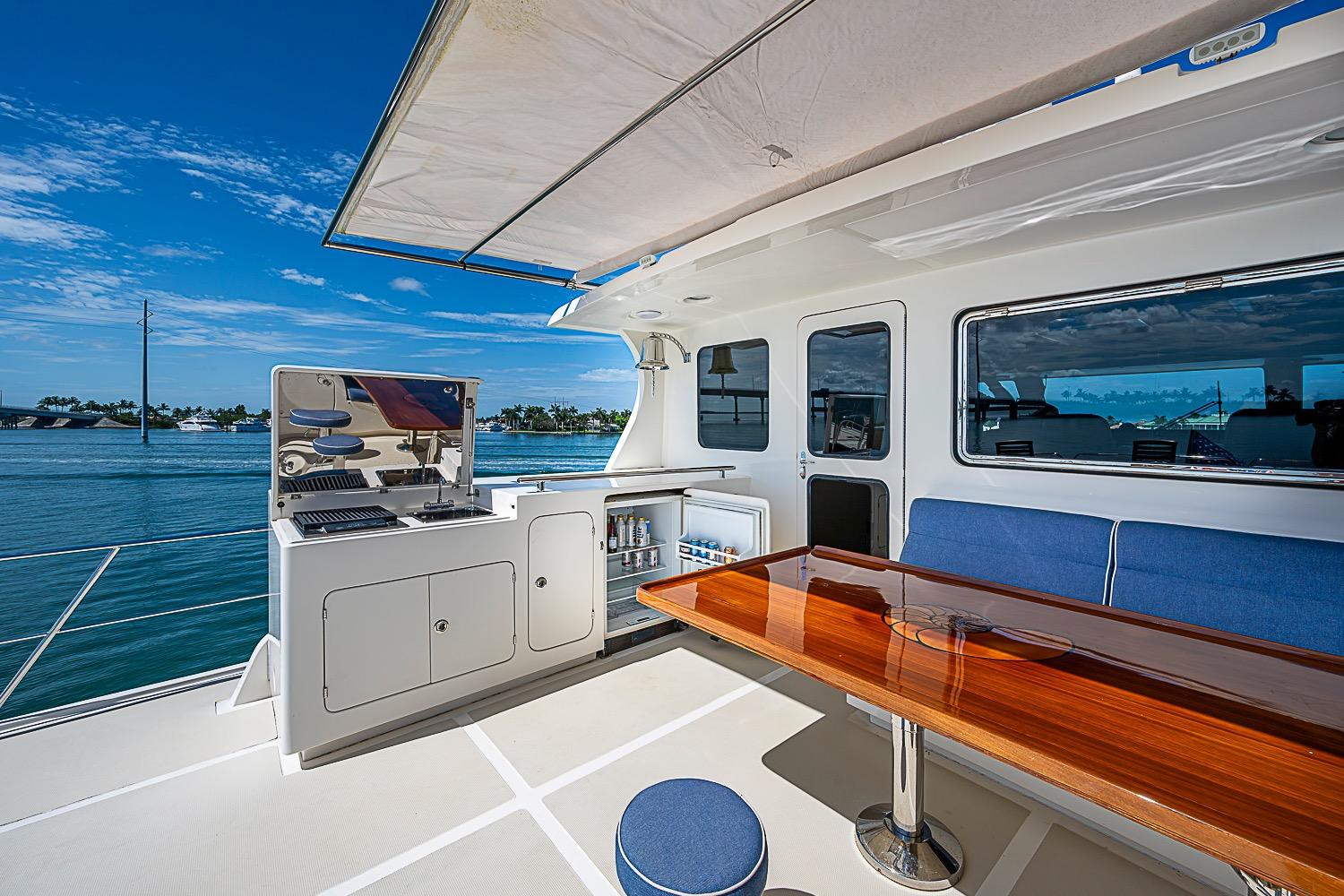 Outdoor seating and grill area on 2014 Marlow 80 Explorer yacht, with ocean view.