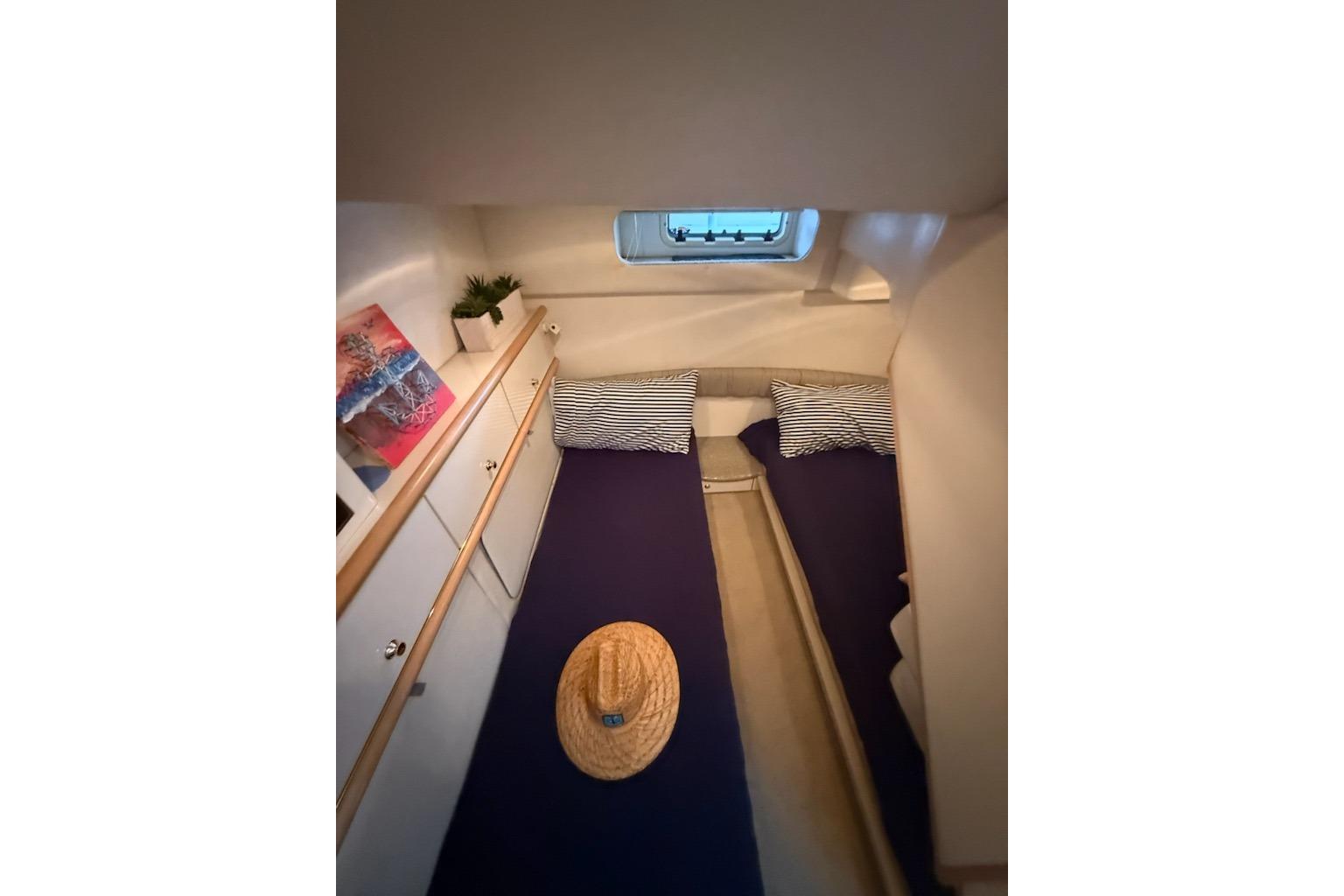 Cozy cabin interior of 1998 Maxum 3700 SCR yacht with twin beds and nautical decor.