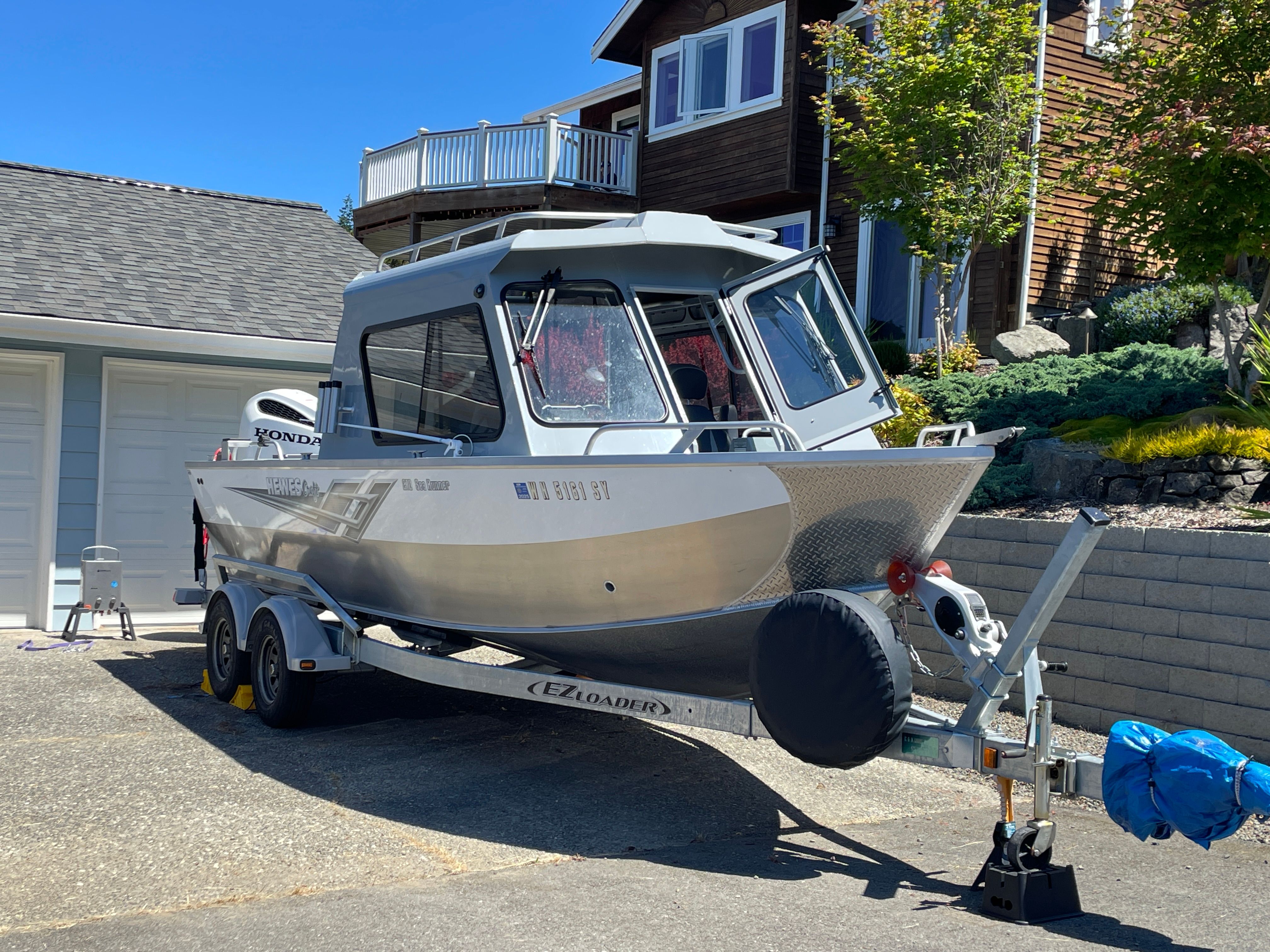 2021 Hewescraft 210 Sea Runner ET Hardtop parked on a trailer in front of a house.