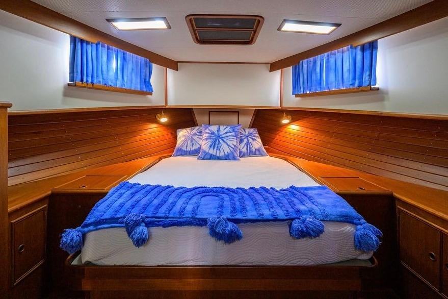 Cozy cabin interior of 1999 Grand Banks 42 Europa with blue accents and wood paneling.