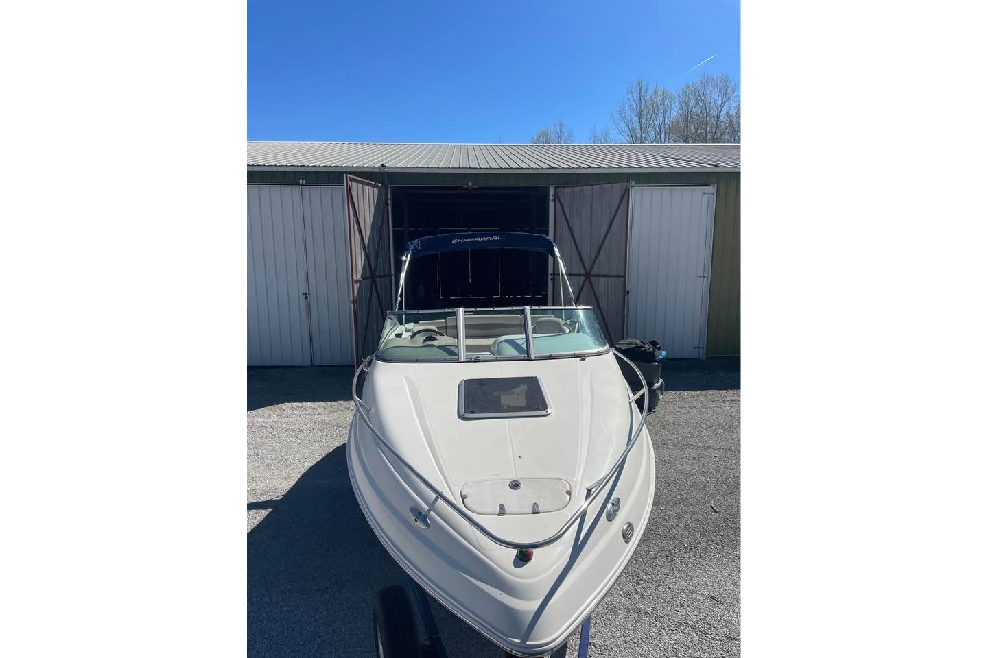 2007 Chaparral 215 SSi boat parked outside a storage shed under clear blue sky.
