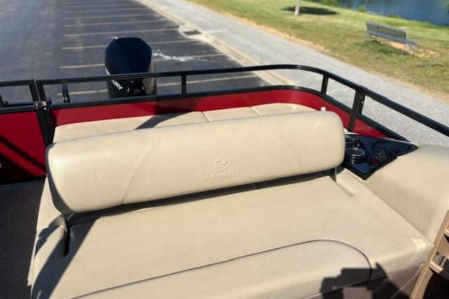 2025 Regency 250 DL3 boat with beige seating and rear motor, parked near a lake.