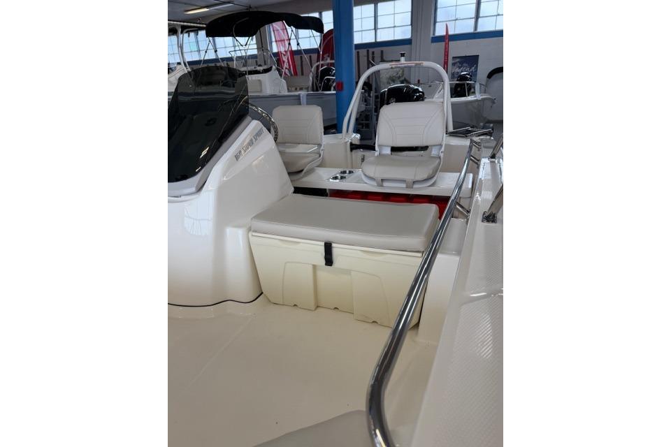 2026 Boston Whaler 160 Super Sport interior with seating and storage, displayed indoors.