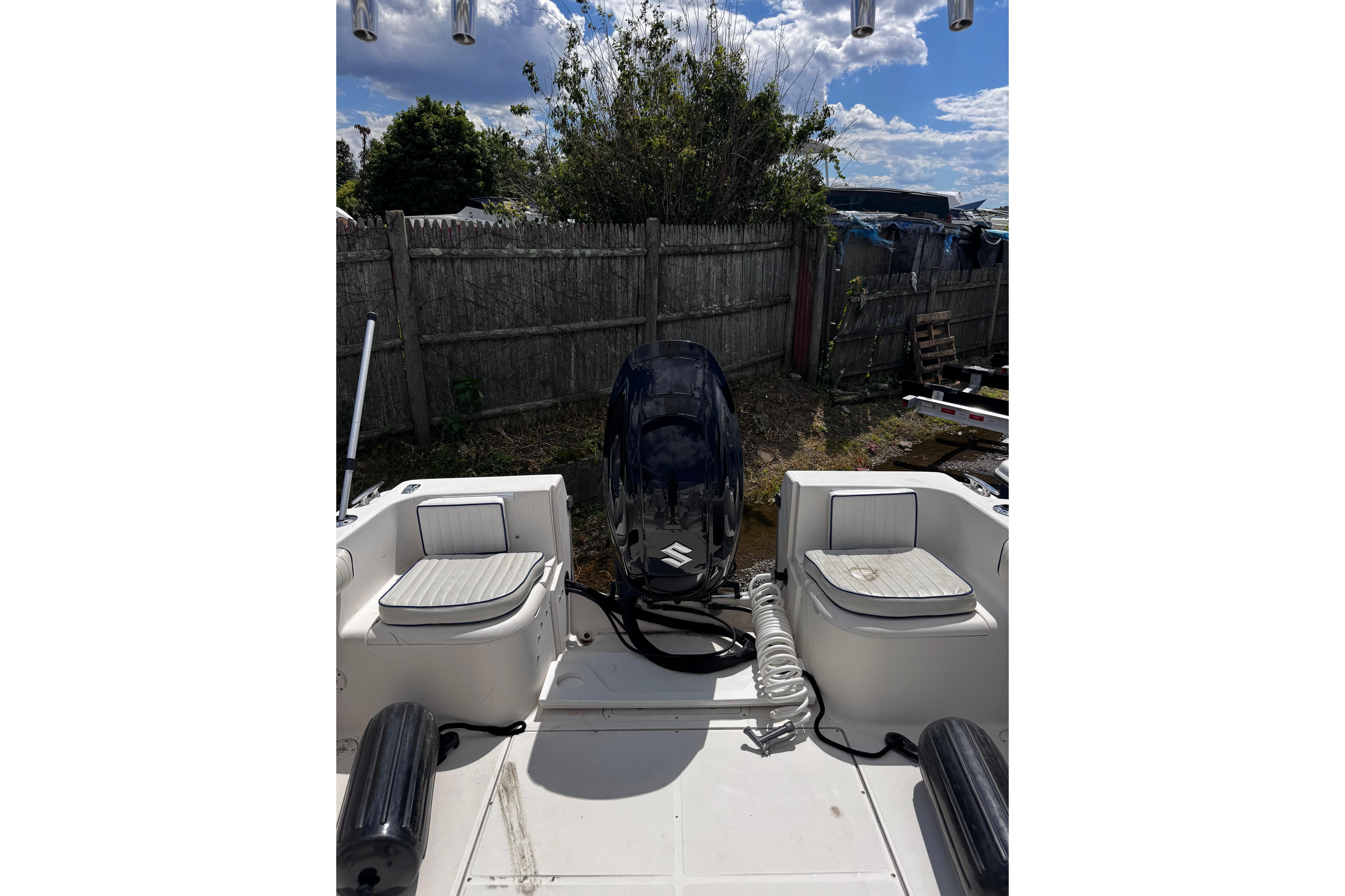 2003 Palm Beach 2200 Dual Console boat with Suzuki outboard motor in a yard.