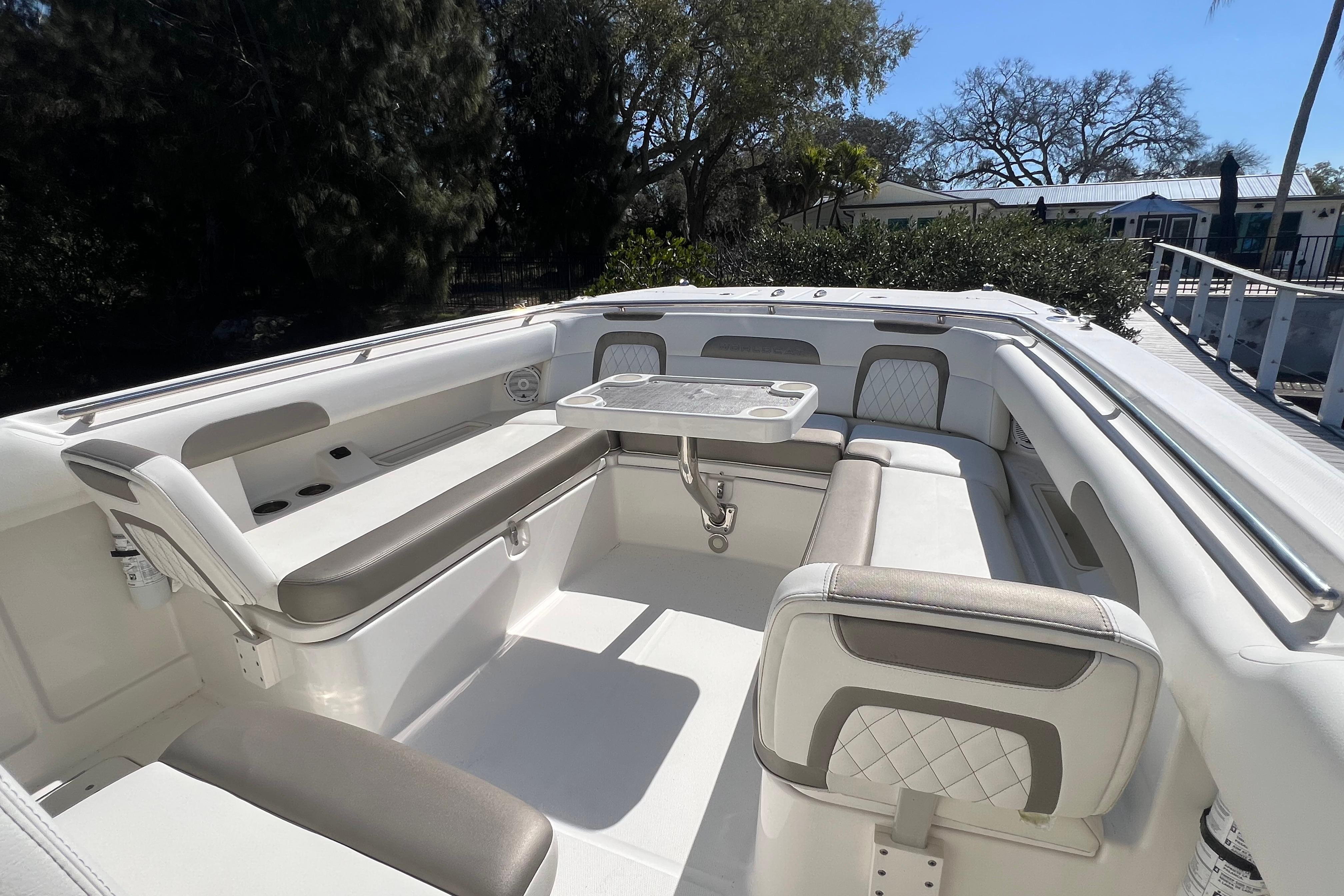 2022 World Cat 280 CC-X boat interior with seating and table, surrounded by trees.