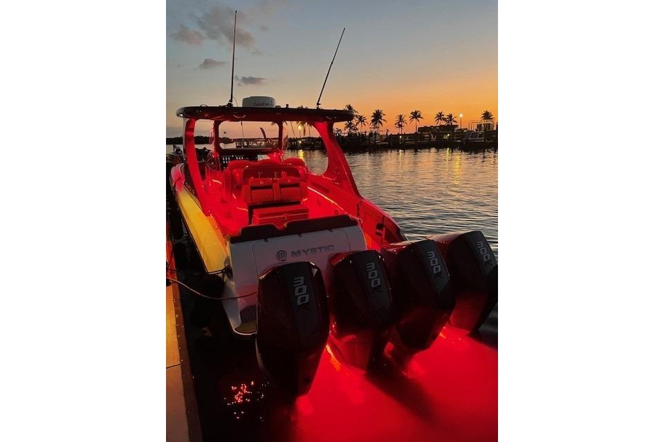 2021 Mystic Powerboats M3800 illuminated at sunset with palm trees in the background.