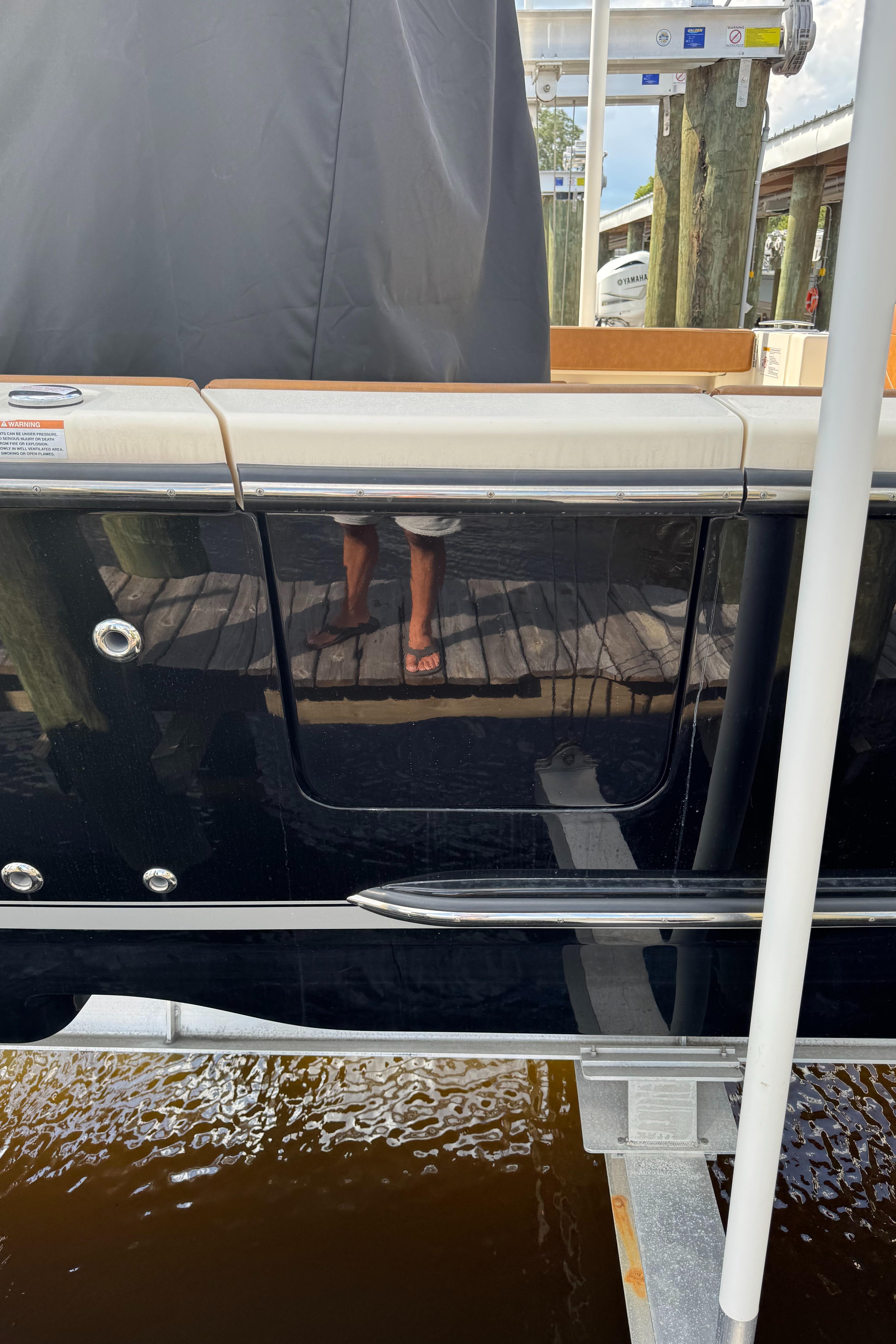 2021 Scout 330 LXF boat docked, reflecting surroundings on glossy black hull.