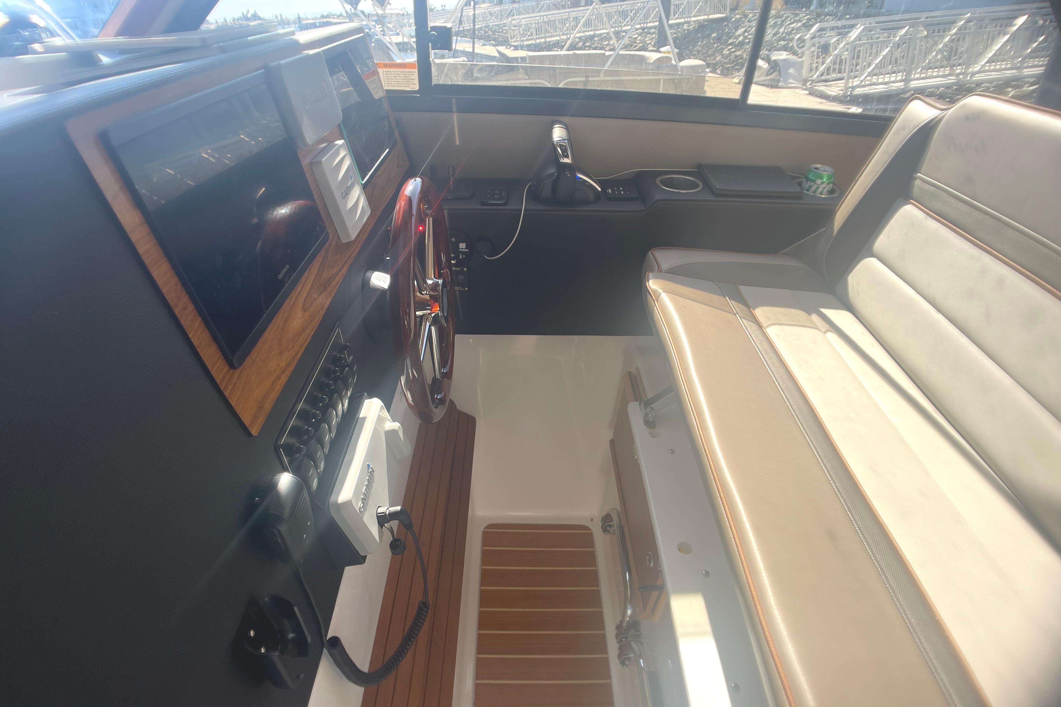 2022 Cutwater Flybridge interior with steering wheel, dashboard, and beige seating.