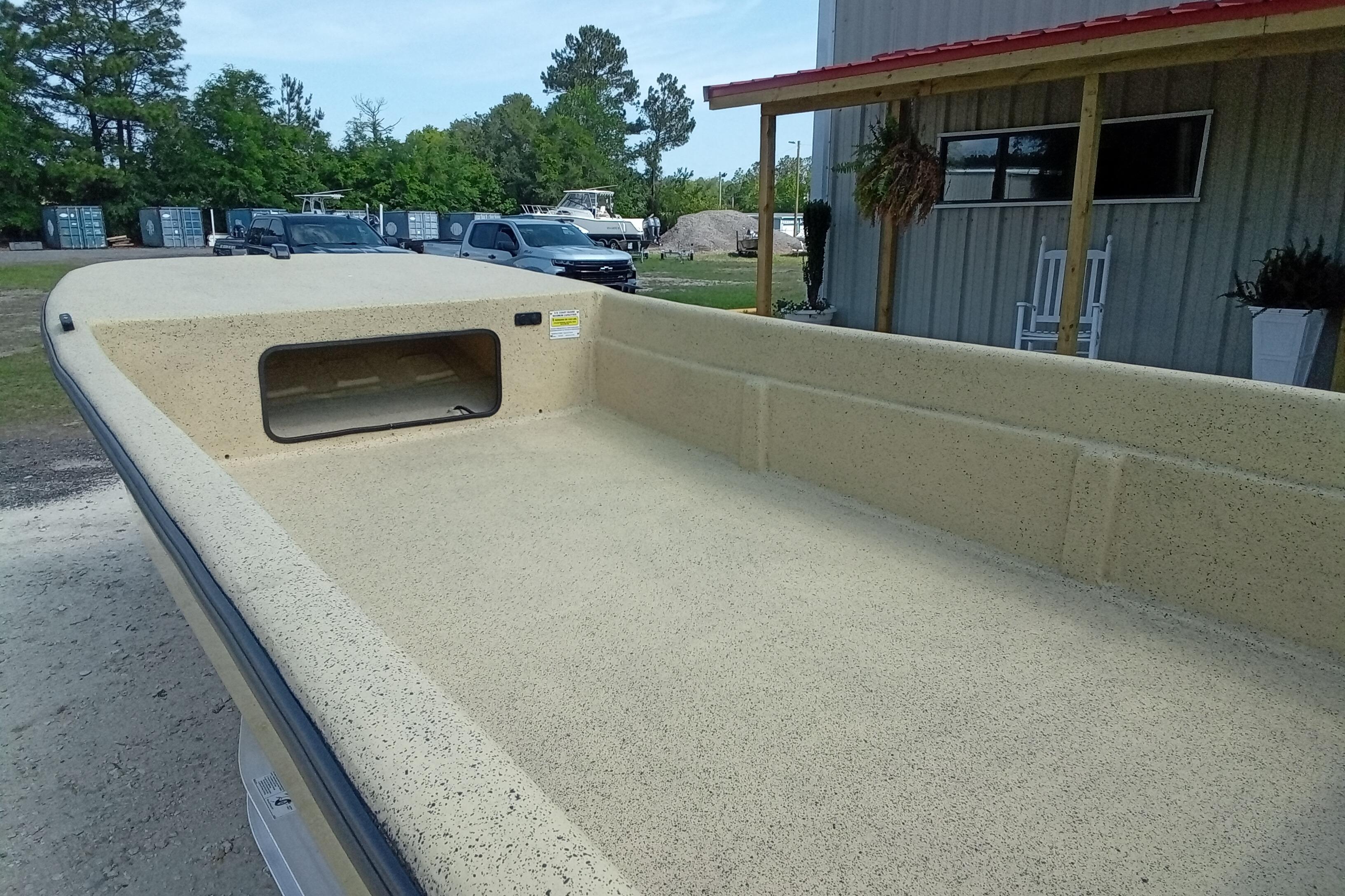 2025 Fibercraft F17 boat with spacious deck, parked outdoors near a building.