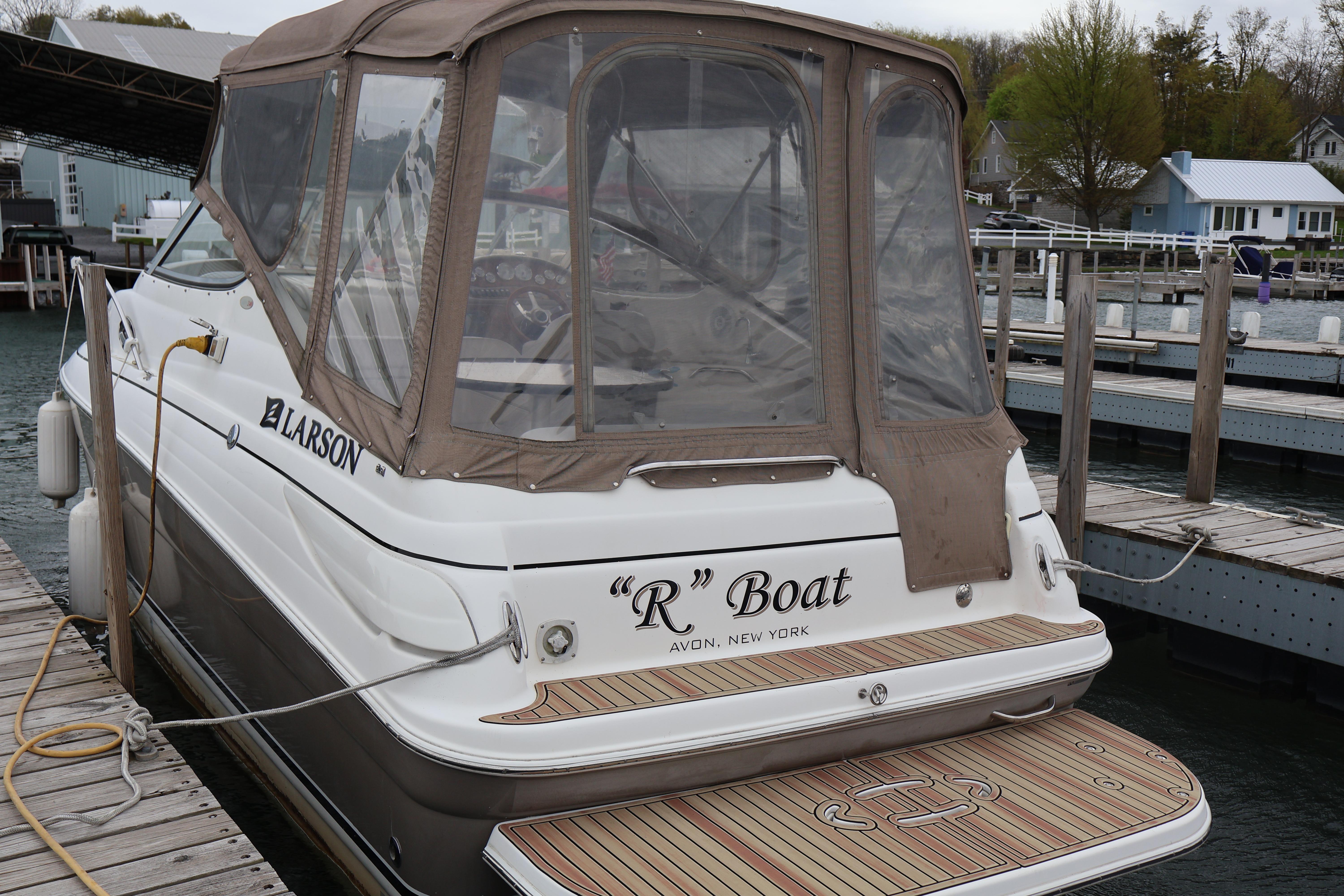 2006 Larson Cabrio 240 boat docked, featuring a covered cabin and wooden deck.