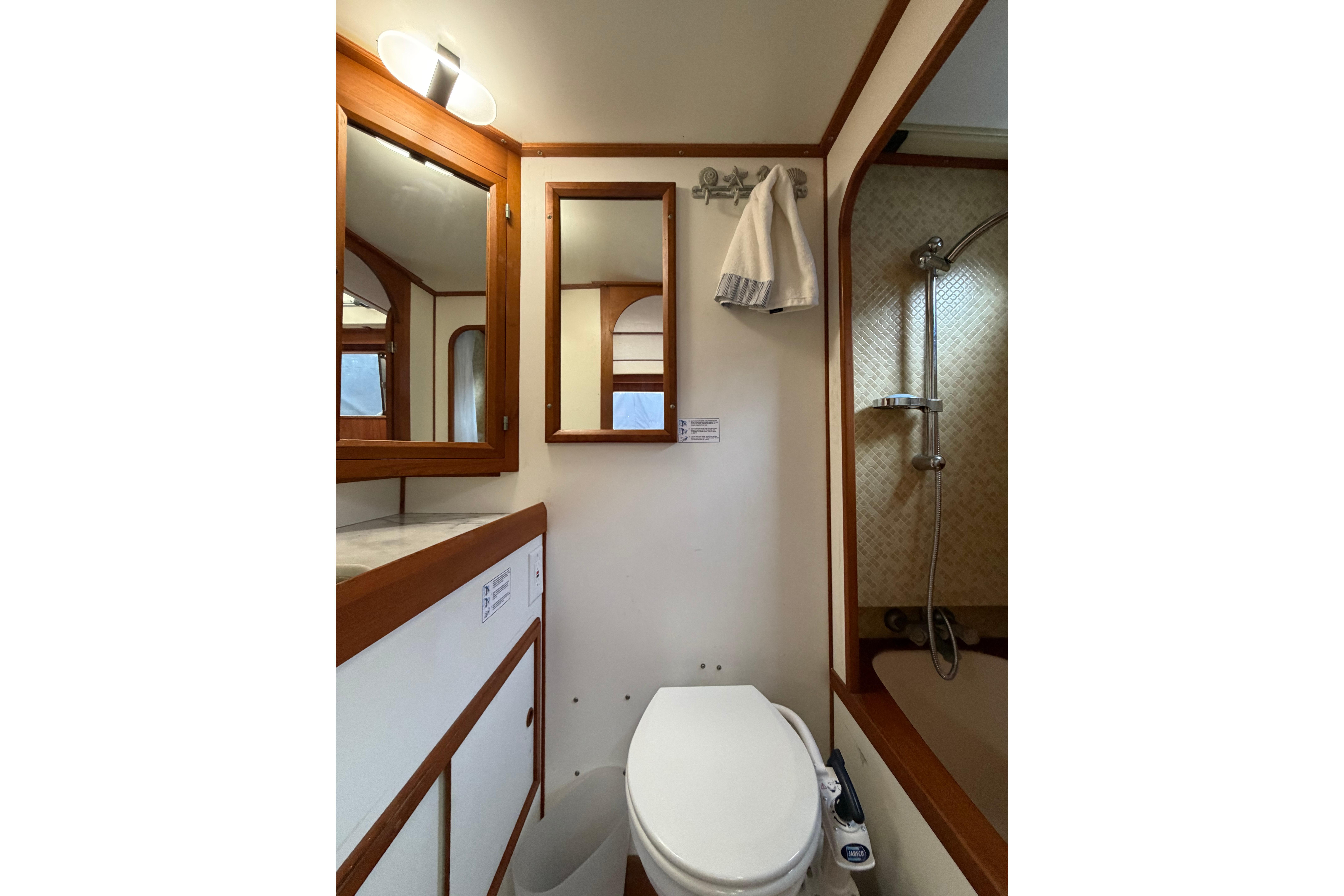 Compact bathroom in a 1988 Monk 36 boat, featuring a shower, toilet, and wooden accents.