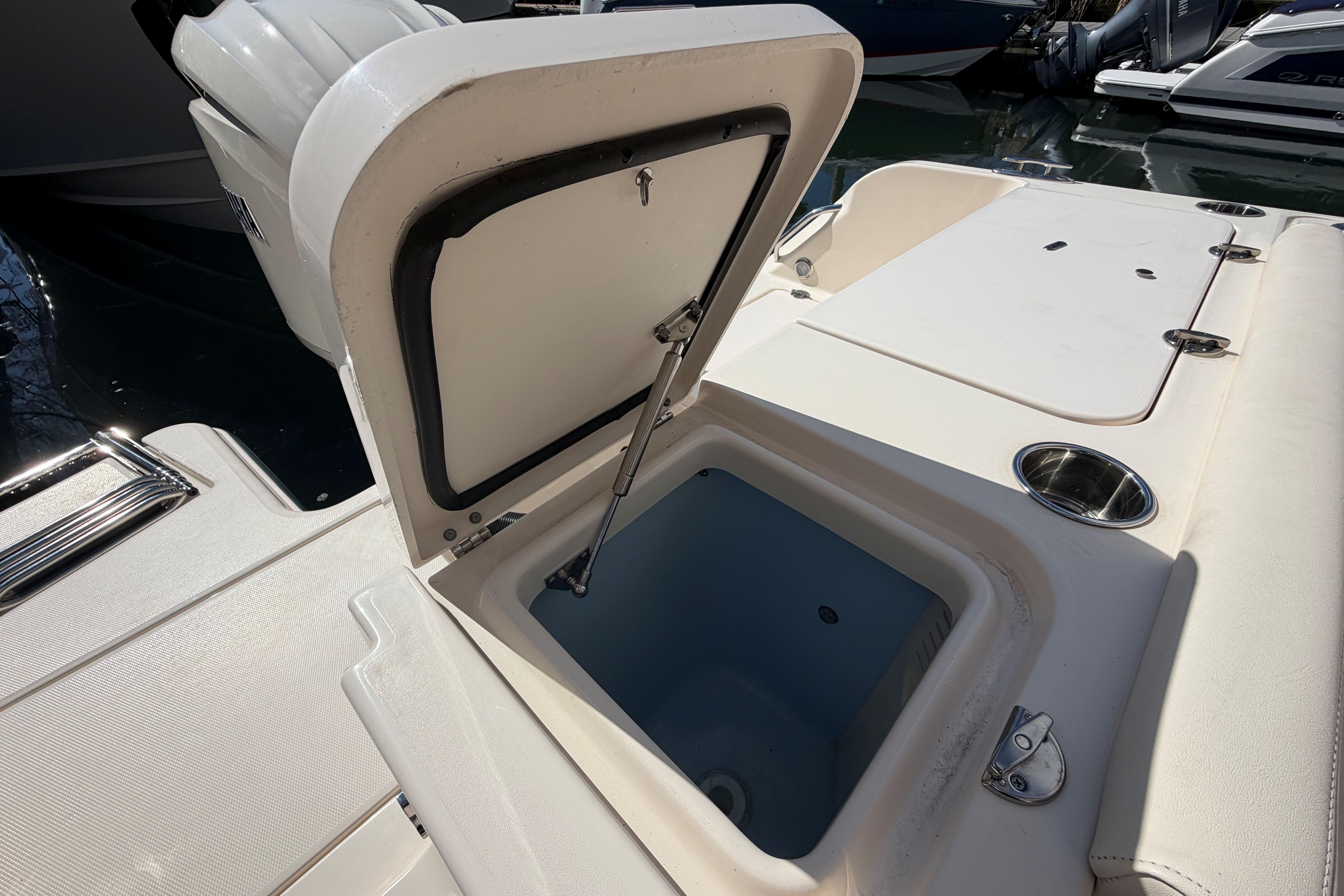 Open storage compartment on 2025 Grady-White Freedom 235 boat, docked near water.