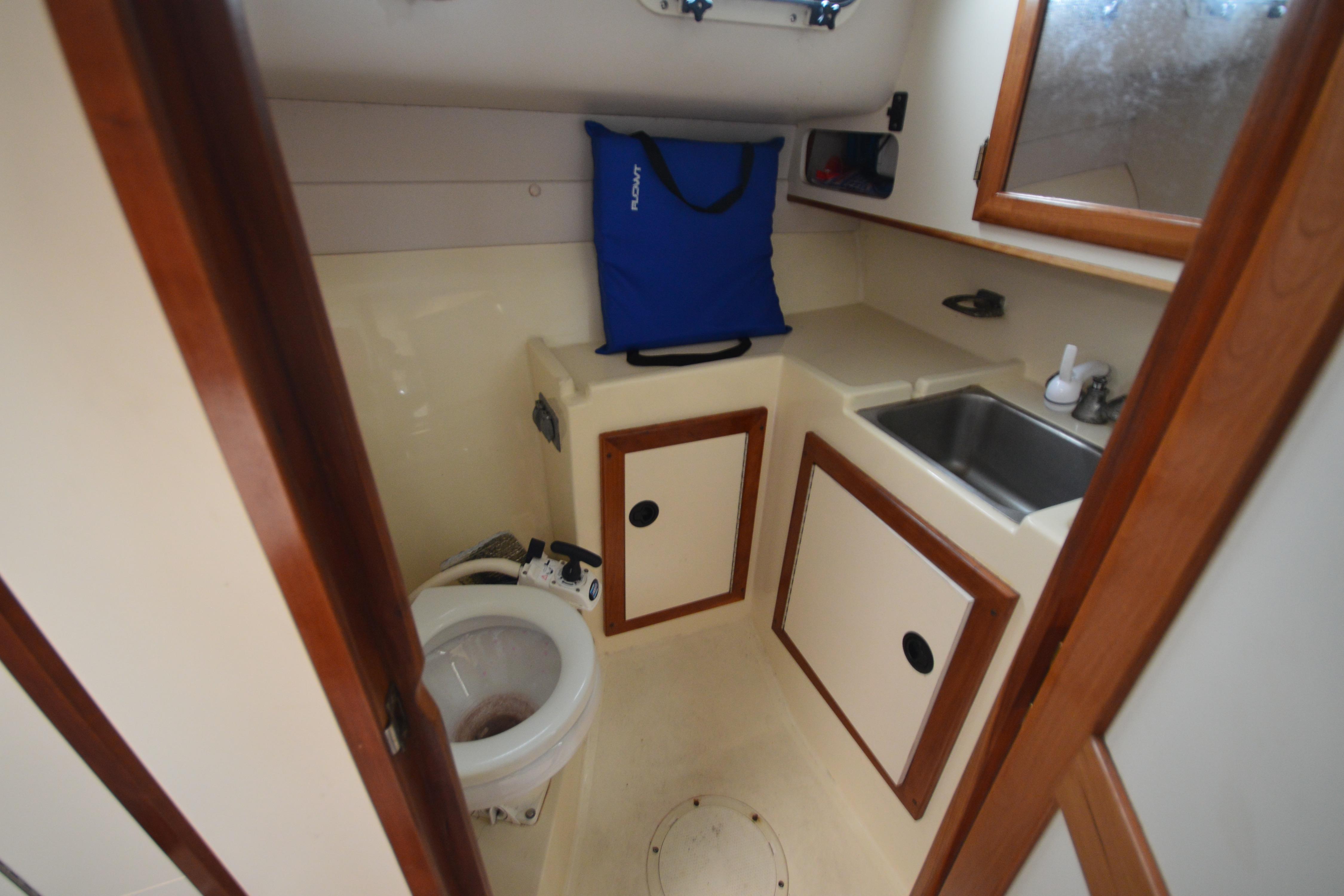 2001 Albin 28 Tournament Express boat bathroom with sink, toilet, and storage cabinets.