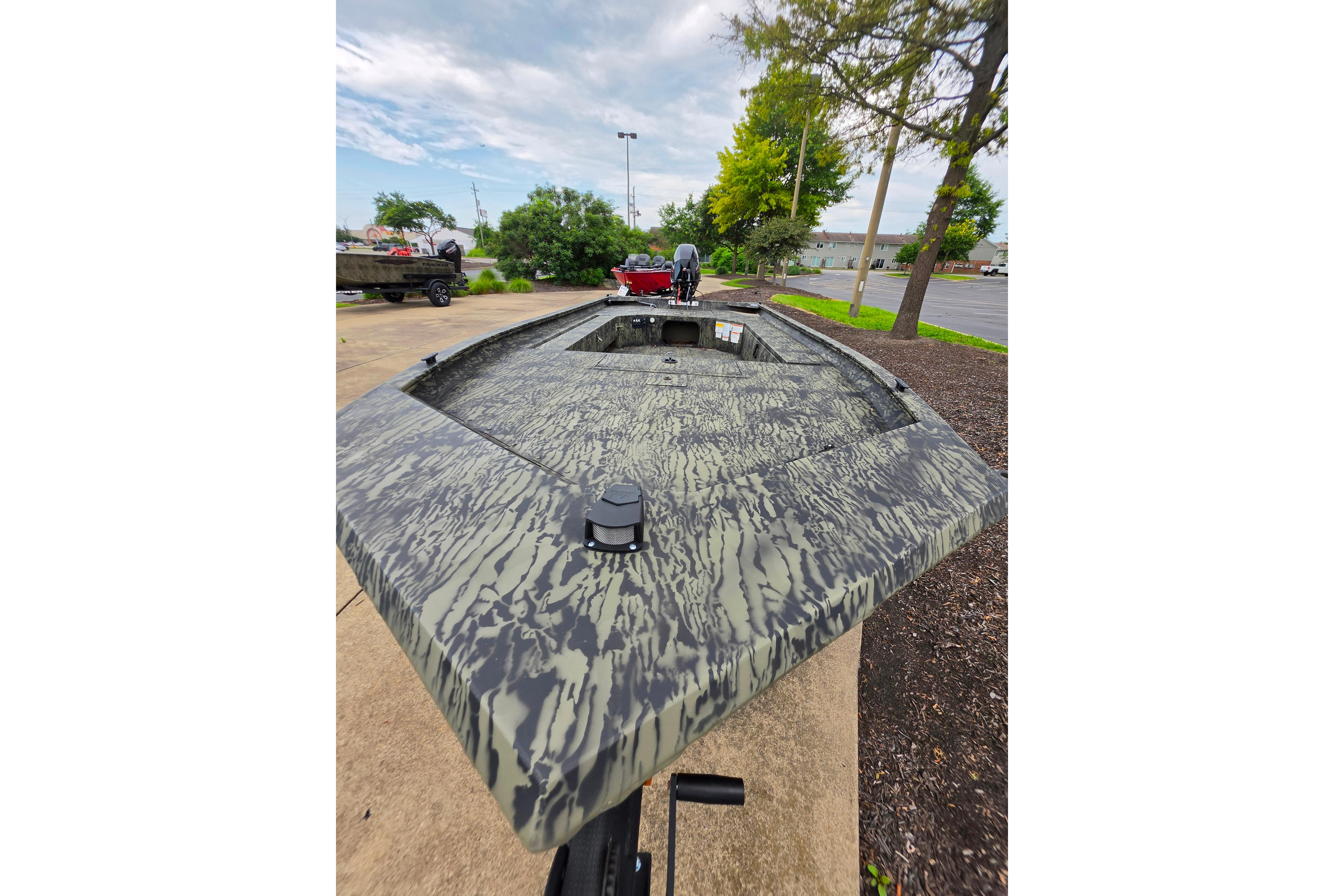 2026 Tracker Grizzly 1654 T Sportsman boat with camouflage design on display outdoors.