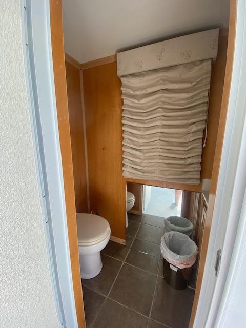 Small bathroom in a 2006 Fantasy houseboat with wooden walls and tiled floor.