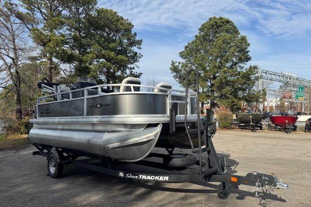 2026 Sun Tracker Bass Buggy 16 XL Select pontoon boat on trailer, parked outdoors.