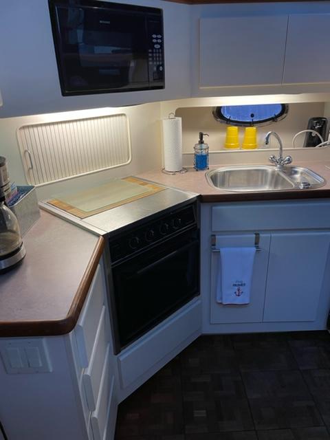 1996 Carver 370 yacht kitchen with sink, stove, microwave, and storage cabinets.