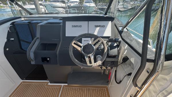 Helm of 2025 Nimbus T11 boat with Simrad navigation system and modern steering wheel.