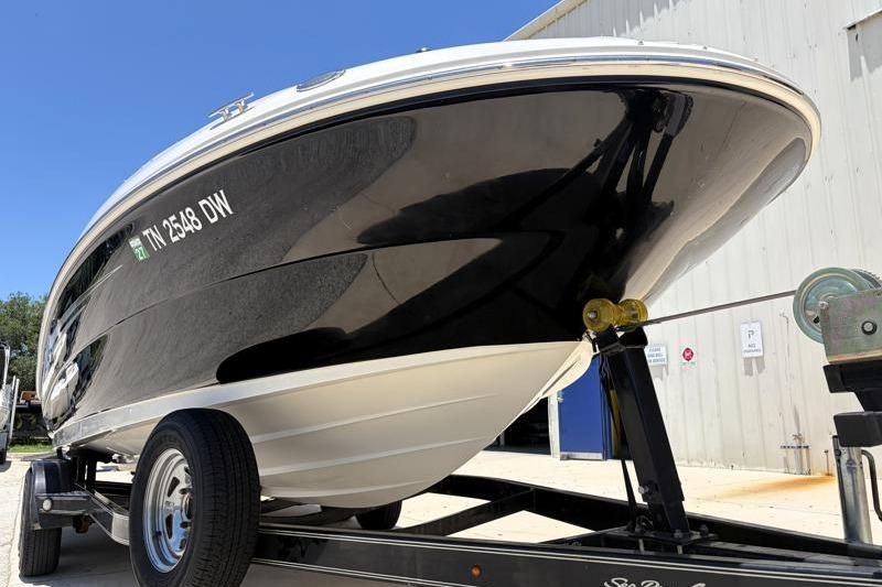 2007 Sea Ray 240 Sundeck boat on trailer, black hull, parked outdoors.