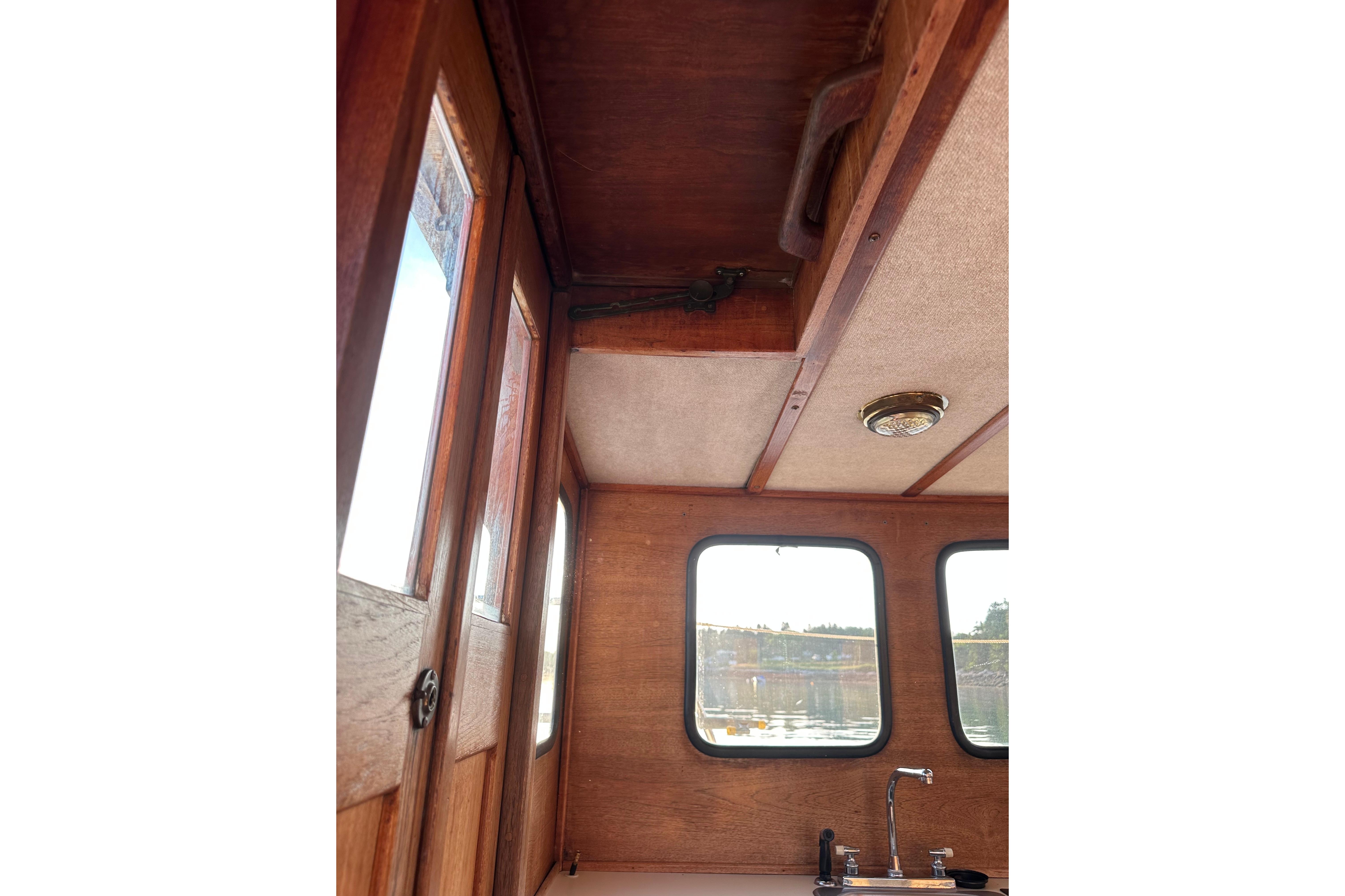 Interior of 1985 Nordic Tug 26 with wooden paneling and windows.