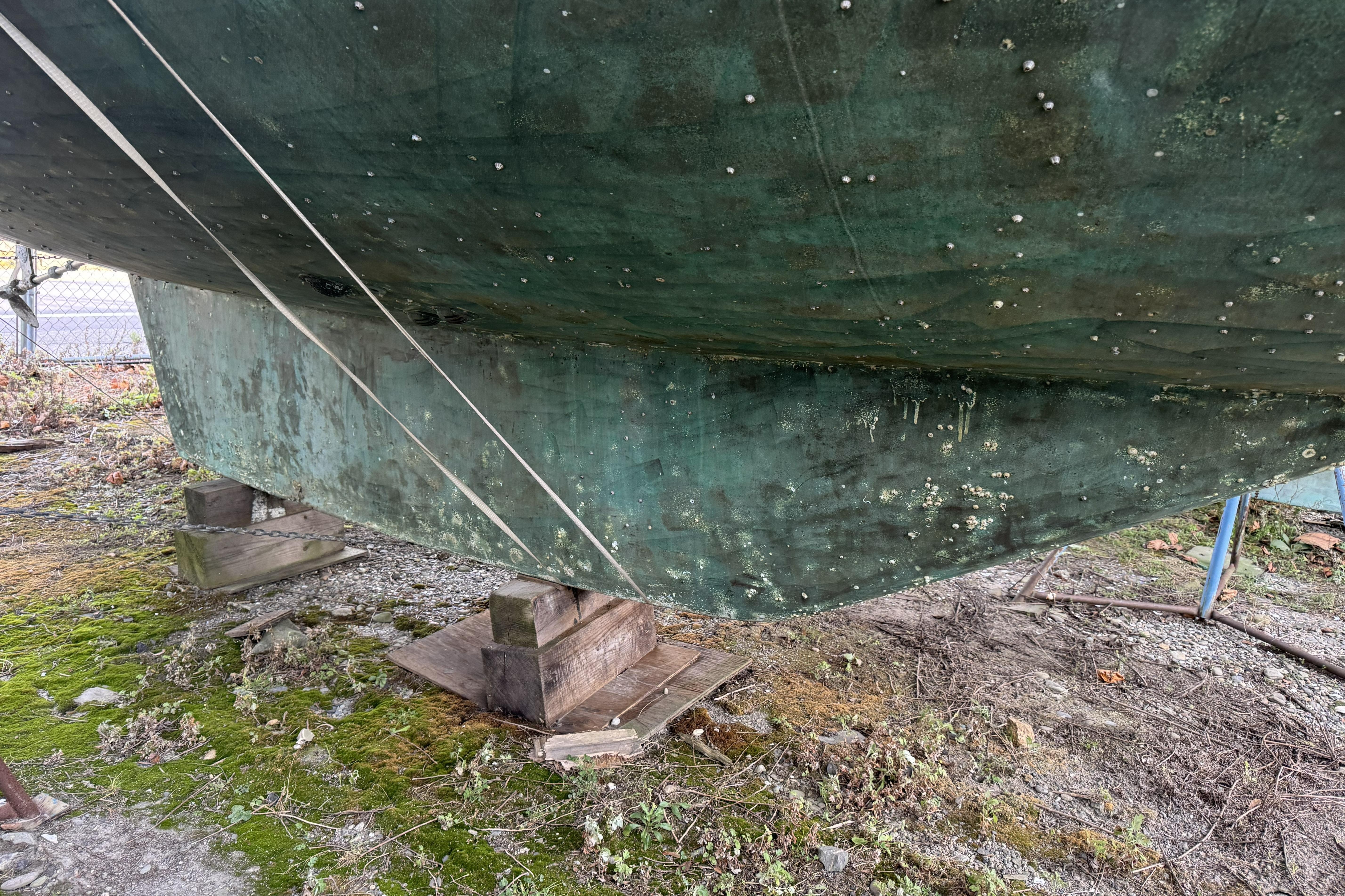 1987 Irwin 38 sailboat hull on stands, showing weathered green surface and marine growth.