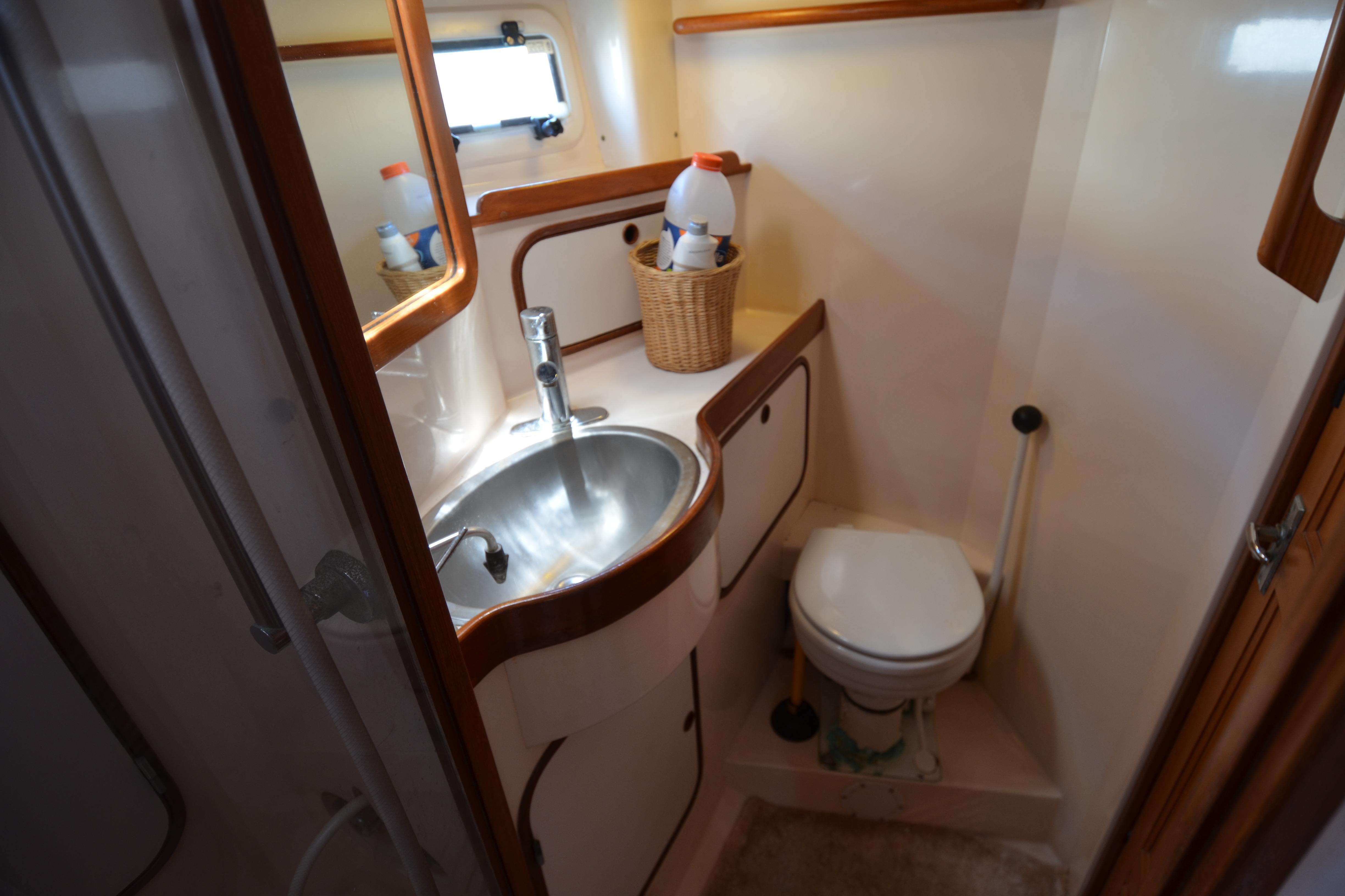 Compact bathroom in 1987 Norseman 400 yacht with sink, toilet, and storage.