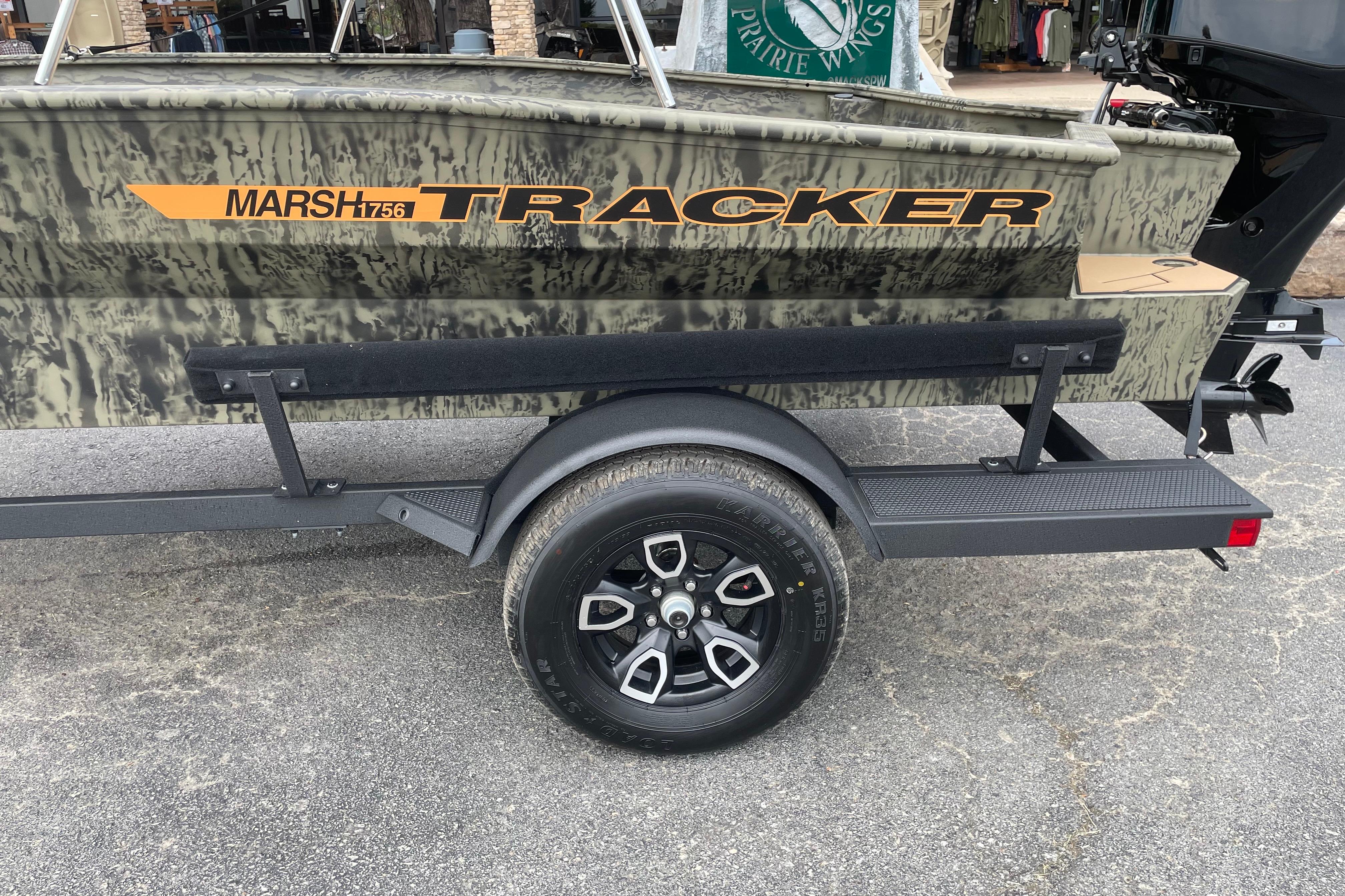 2026 Tracker Grizzly 1756 T Marsh boat on trailer, camouflage design, side view.