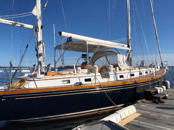 An elegant sailboat with a blue hull and white sails docked at a pier.