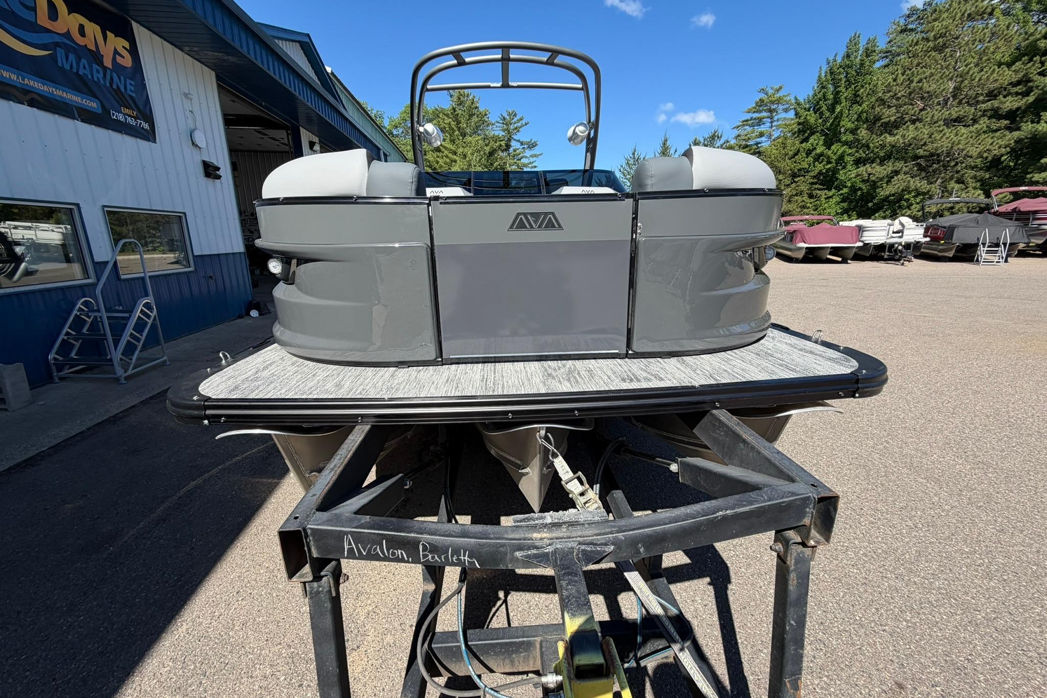 2026 Avalon Excalibur LTD Quad Lounge boat on trailer at dealership.