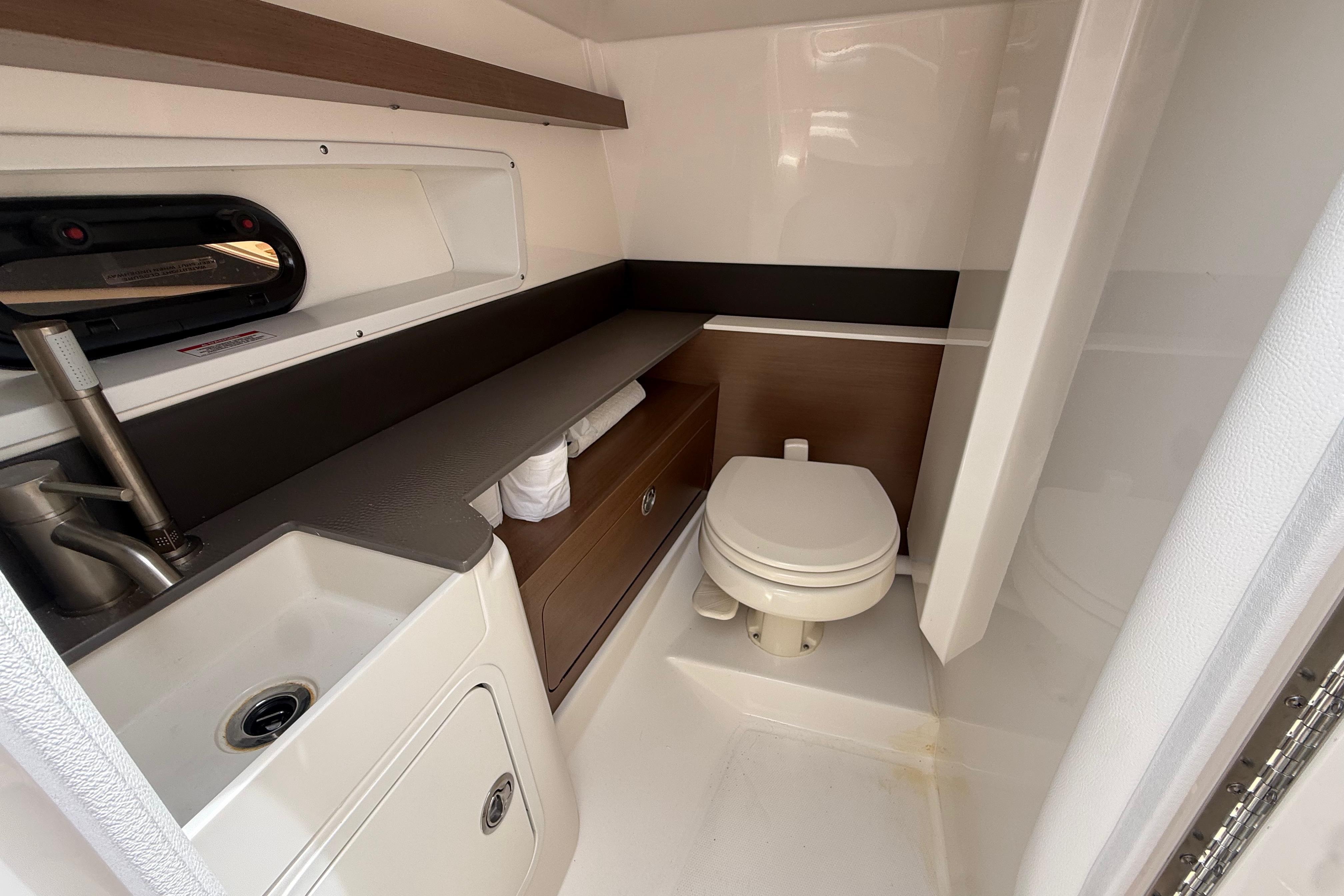 2022 Sea Ray SDX 290 Outboard bathroom with sink, toilet, and storage.