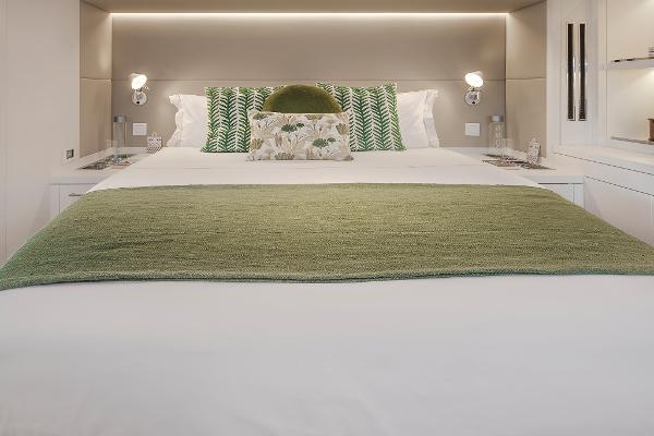 Luxurious bedroom interior of 2025 Lagoon SIXTY 5 yacht with green accents.