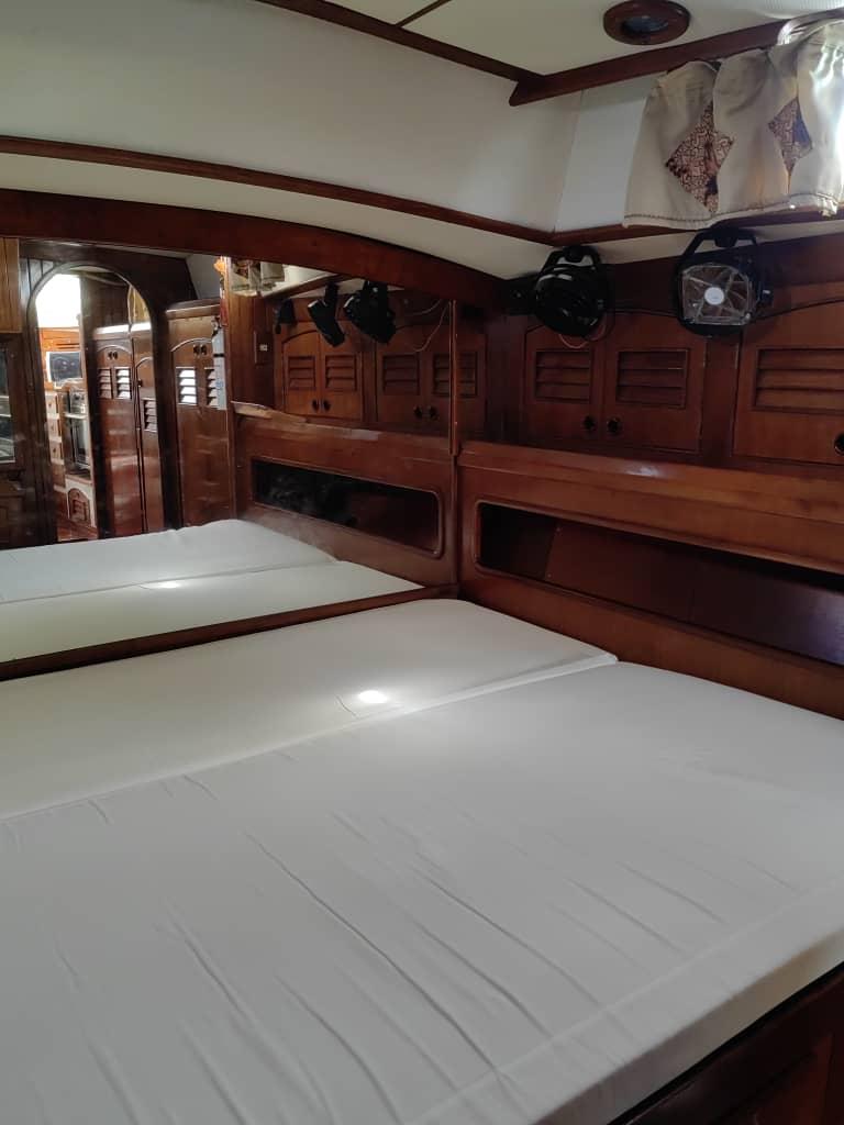 Interior of 1984 Mao Ta 42 yacht with wooden furnishings and white bedding.