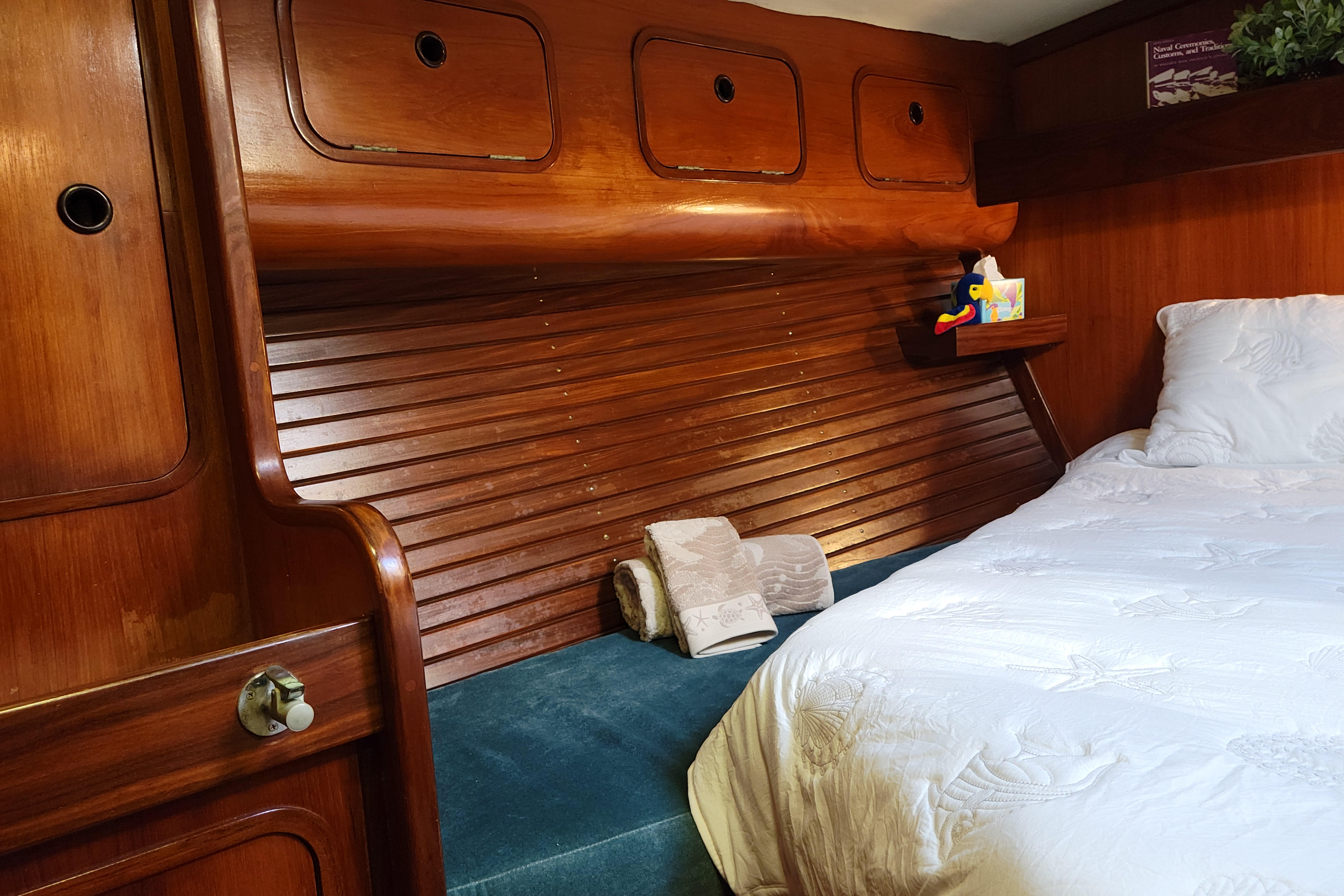 Cozy cabin interior of 1986 Beneteau Idylle 15.50 sailboat with wooden accents and bedding.