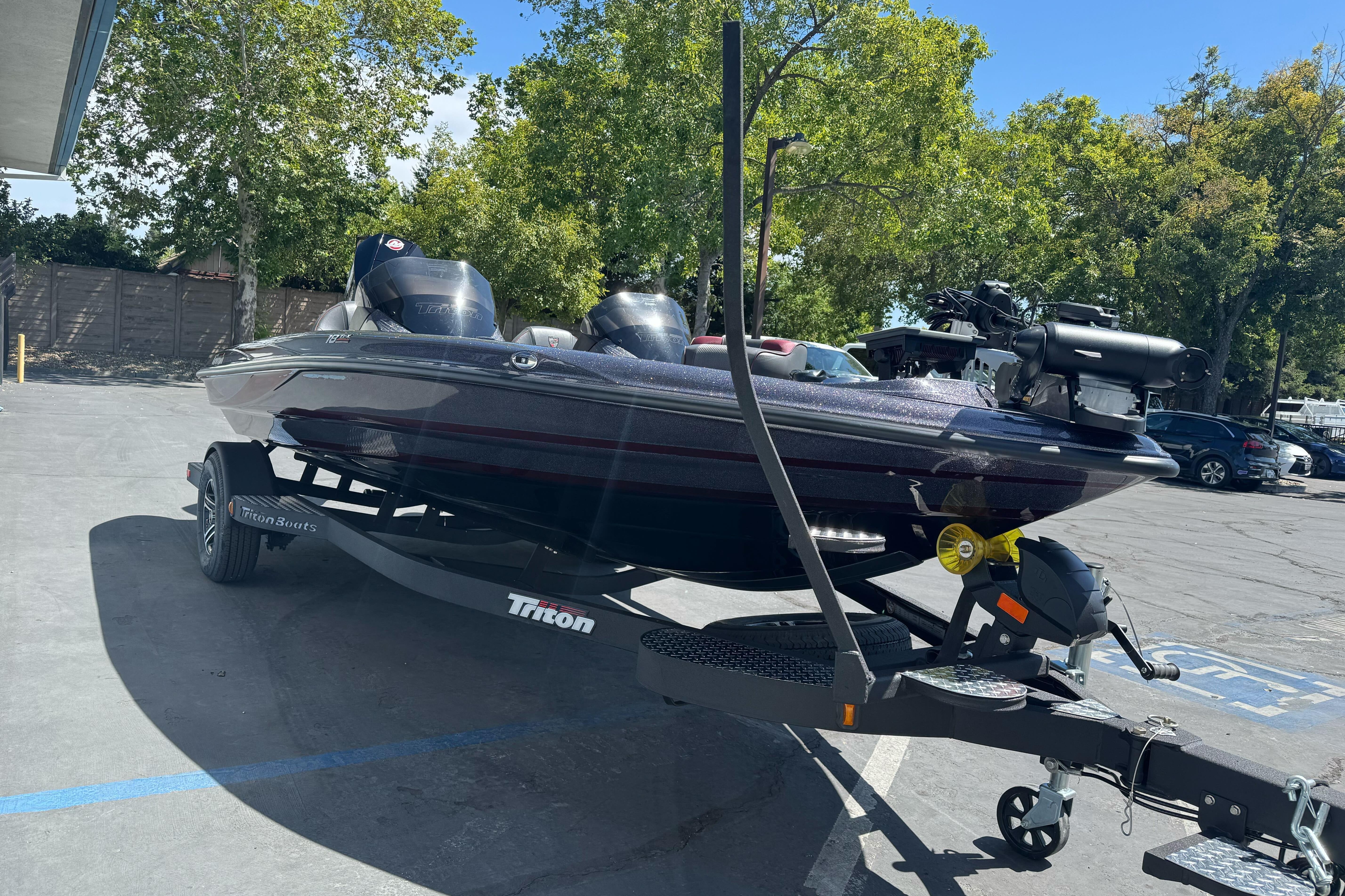 2026 Triton 18 TrX boat on trailer in parking lot, surrounded by trees.
